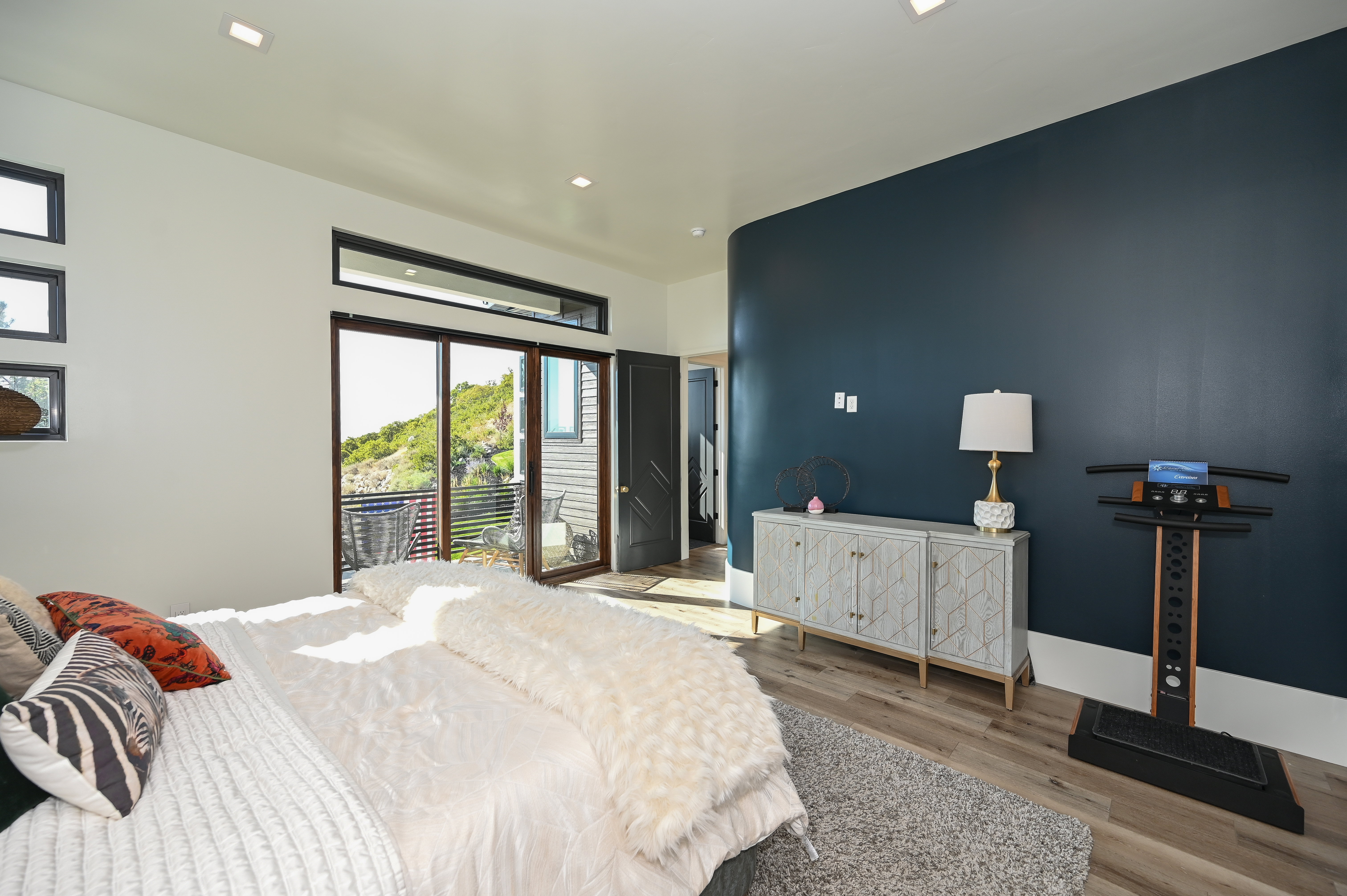 Room featuring wood-finish flooring, a contemporary dark accent wall, recessed lighting, and a glass sliding door providing access to an outdoor area
