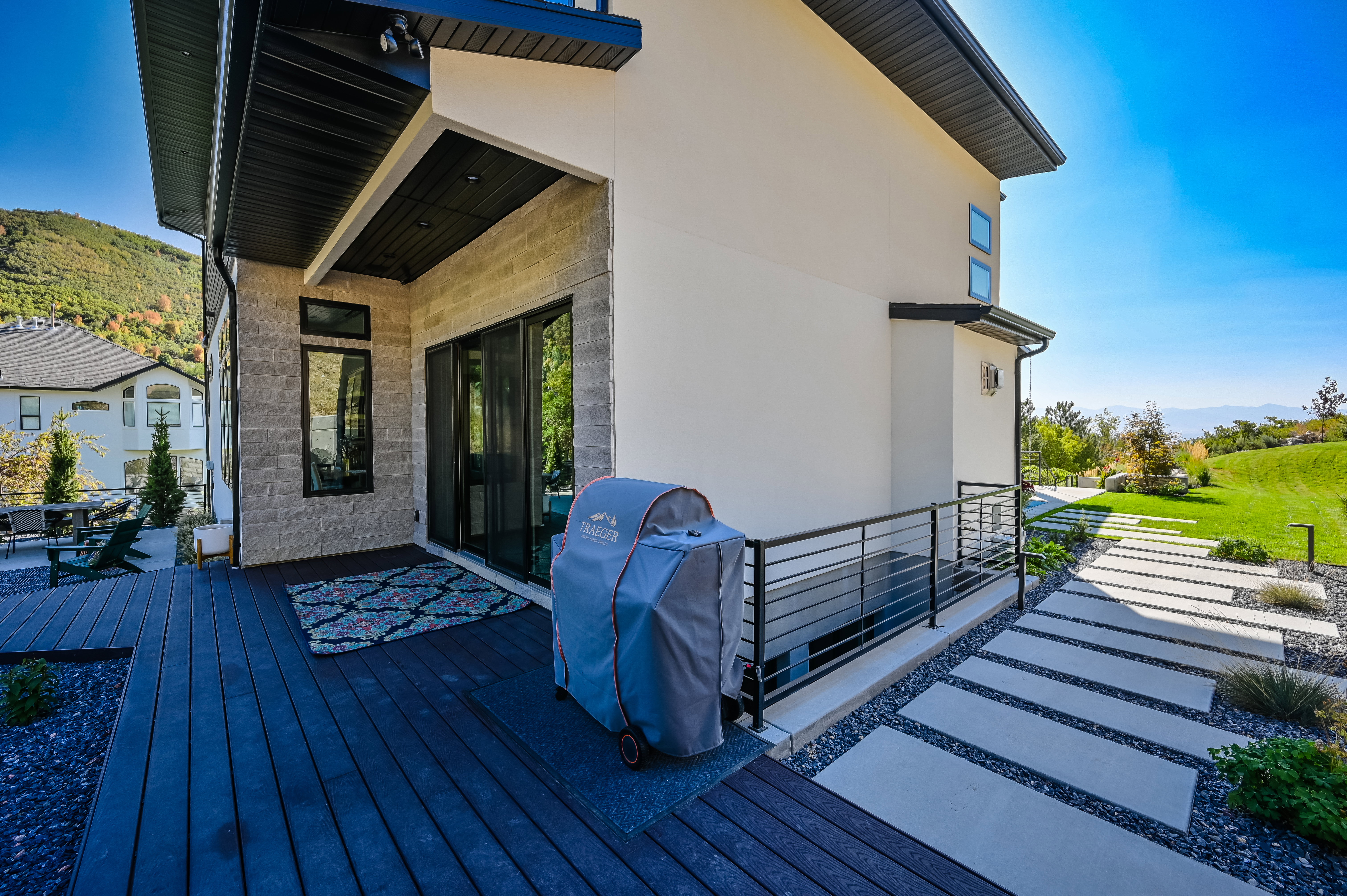 Exterior deck featuring dark wood-finish flooring, a contemporary black railing, and a concrete paver walkway