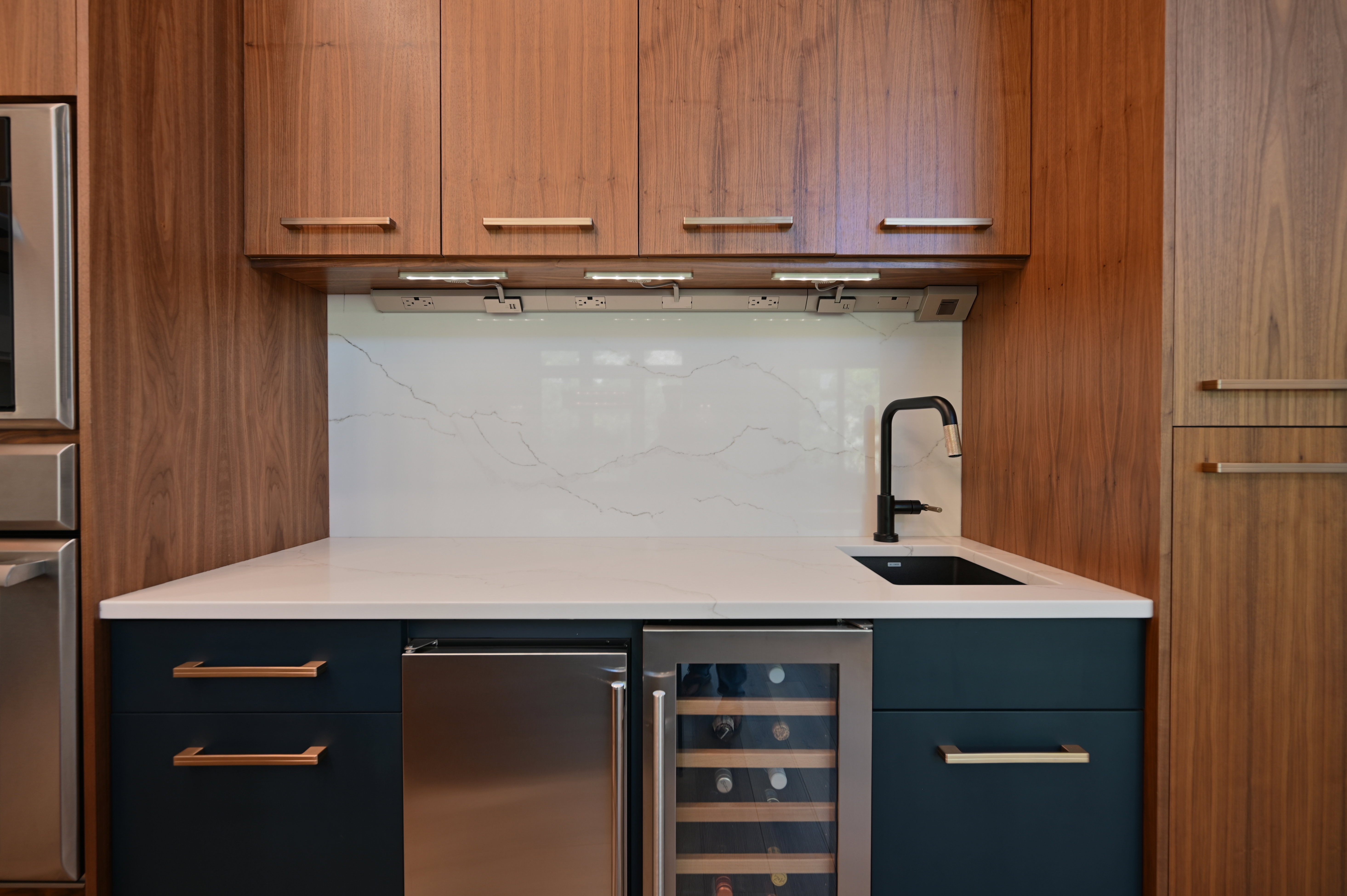 Contemporary wet bar featuring wood-grain cabinetry and dark blue lower cabinets