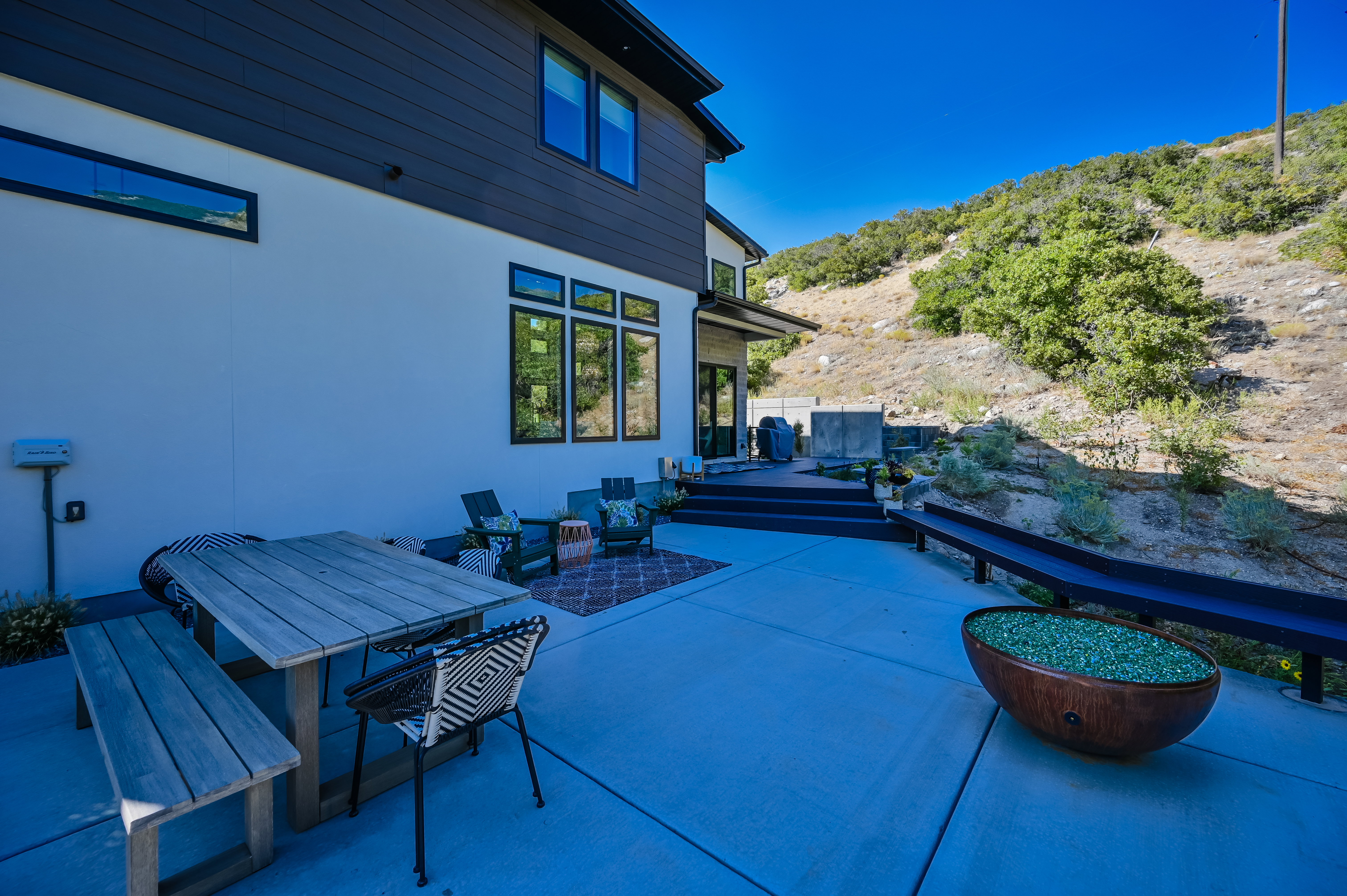 Spacious concrete patio with dark siding and white stucco exterior