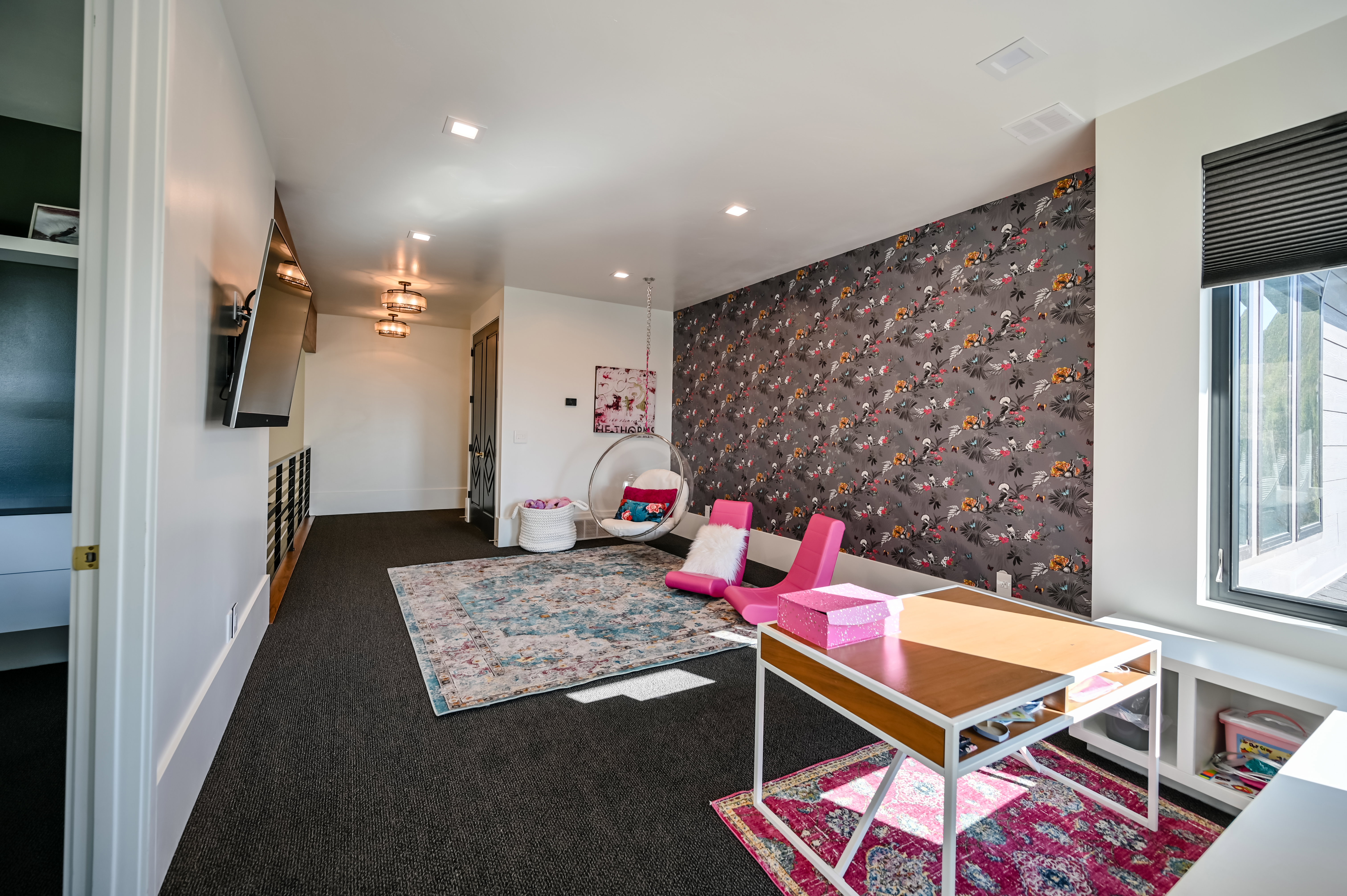 Spacious room featuring patterned accent wall, recessed lighting, large window with integrated blinds, built-in shelving, and dark carpeting