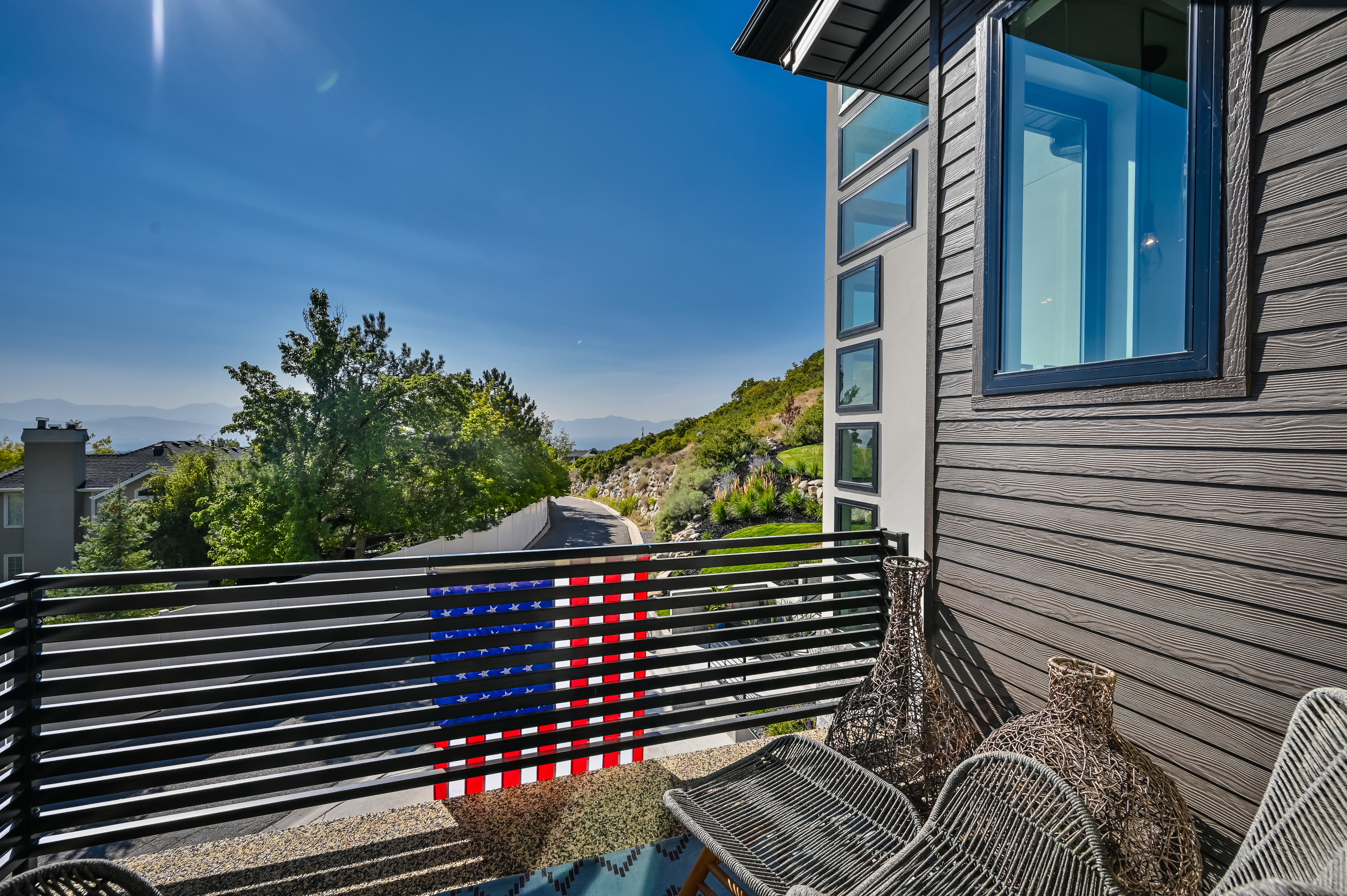 Upper-level balcony featuring horizontal slat railing, gravel flooring, and mountain scenery