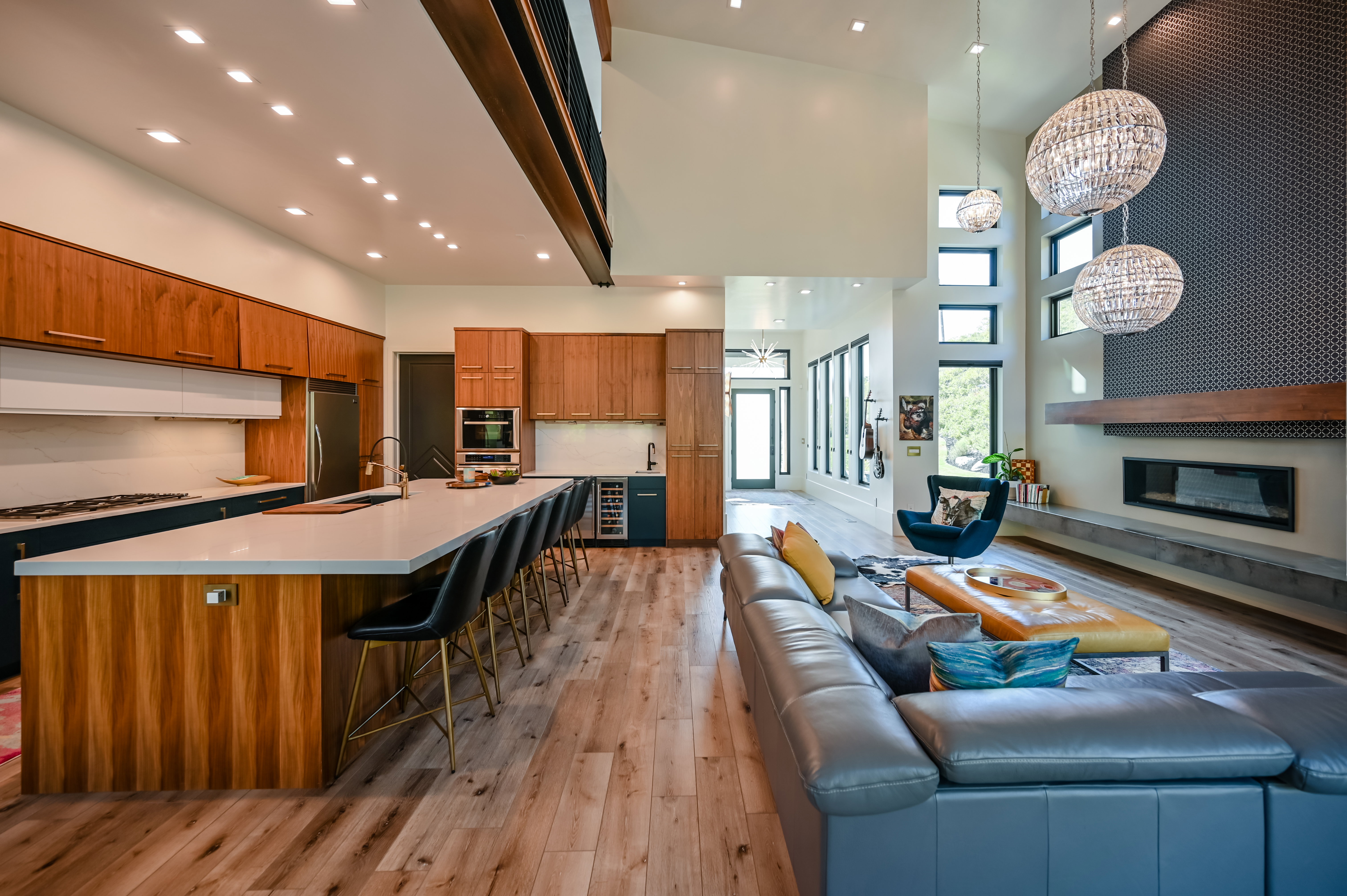 Open-concept living area with wood-finish flooring, a contemporary fireplace, and high vaulted ceilings