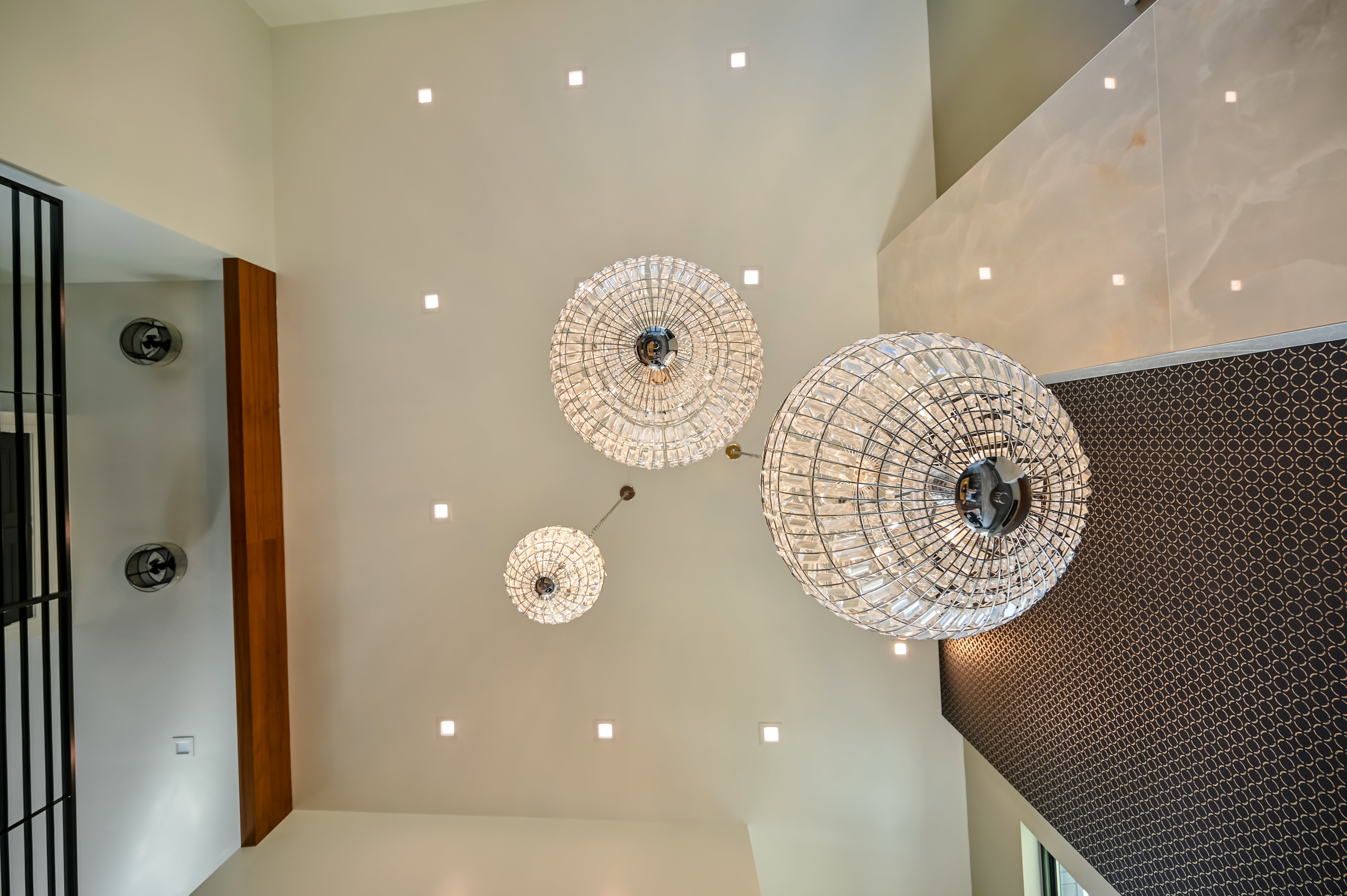 Grand ceiling featuring three crystal chandeliers and recessed lighting