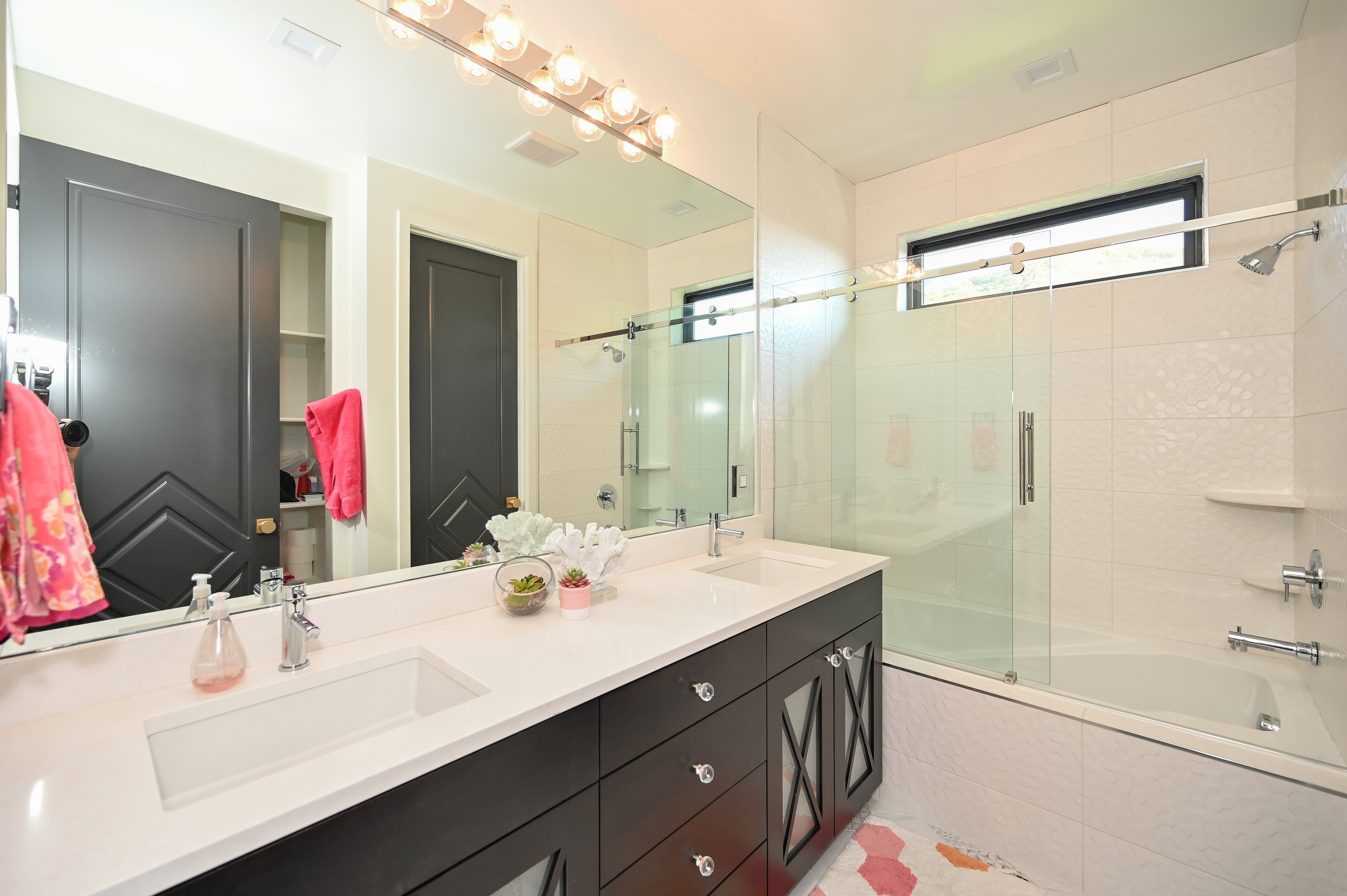 Contemporary bathroom featuring a double vanity with integrated sinks, a white countertop, and dark wood-finish cabinetry