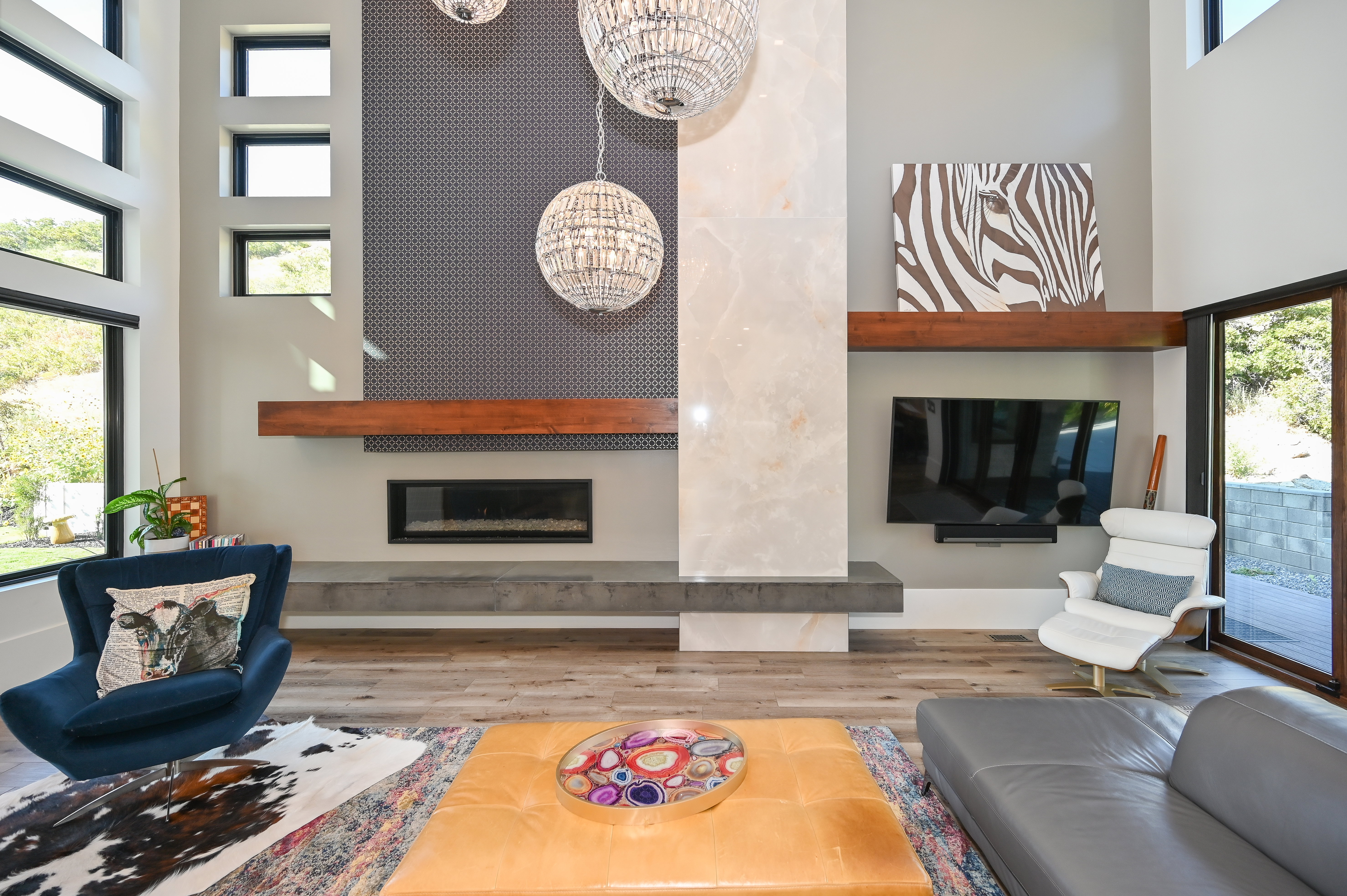 Double-height living area featuring a linear fireplace with a concrete hearth, a striking stone-paneled accent wall, and wood-finish flooring