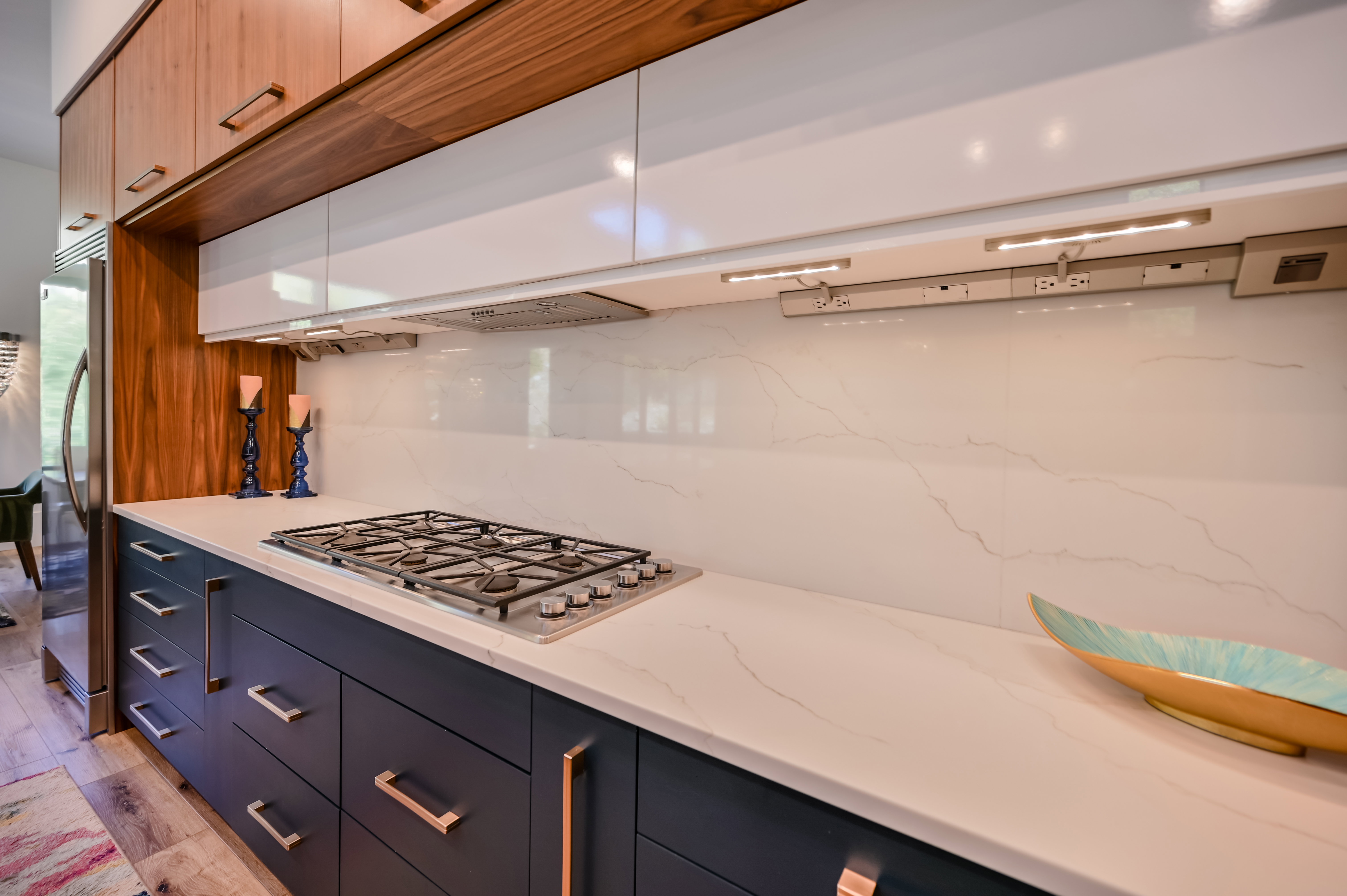 Kitchen featuring a gas cooktop, sleek white countertops, and a full-height white backsplash with subtle veining