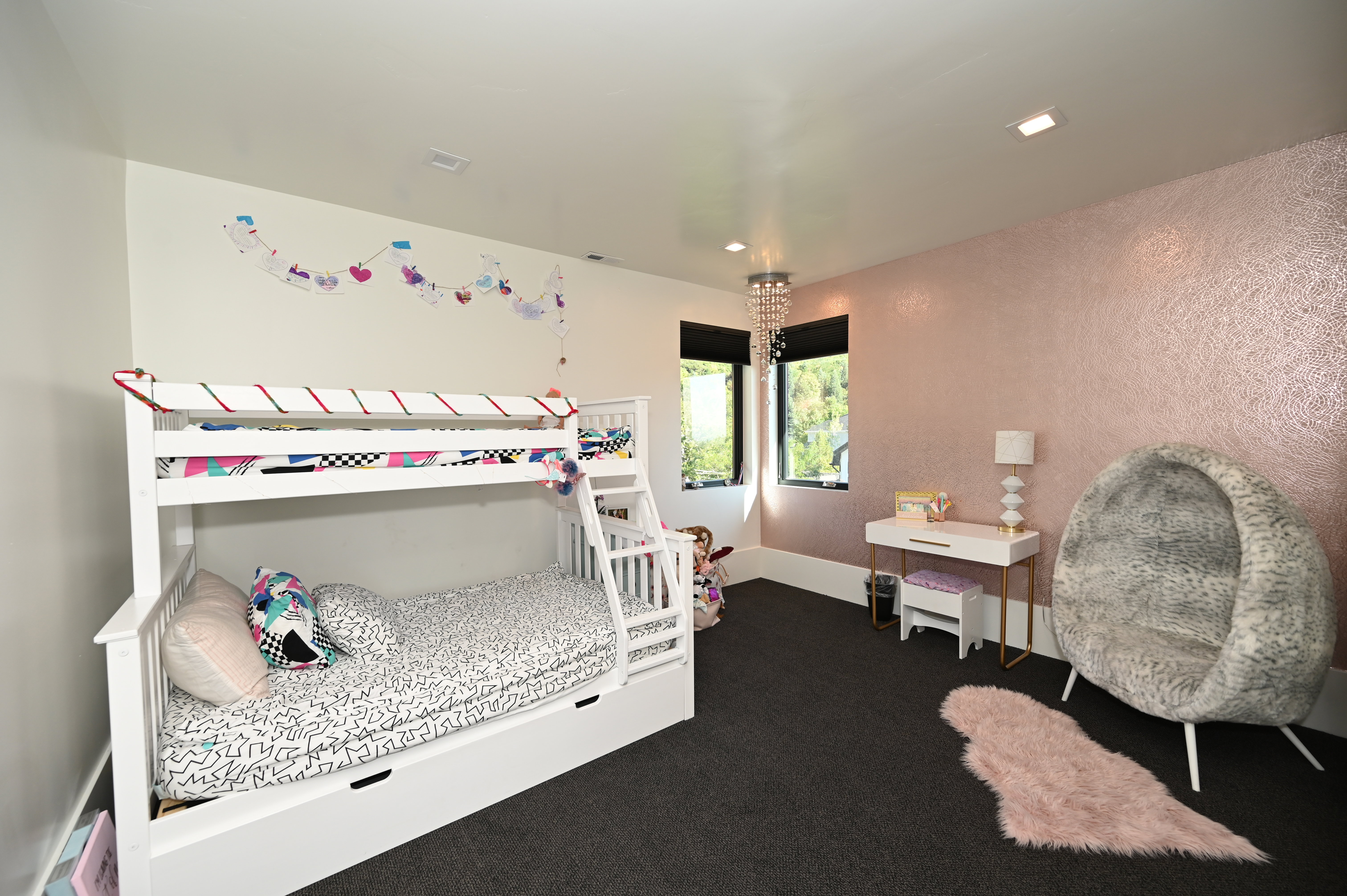 Spacious room featuring dark carpeting, white baseboards, and a textured accent wall with a metallic finish