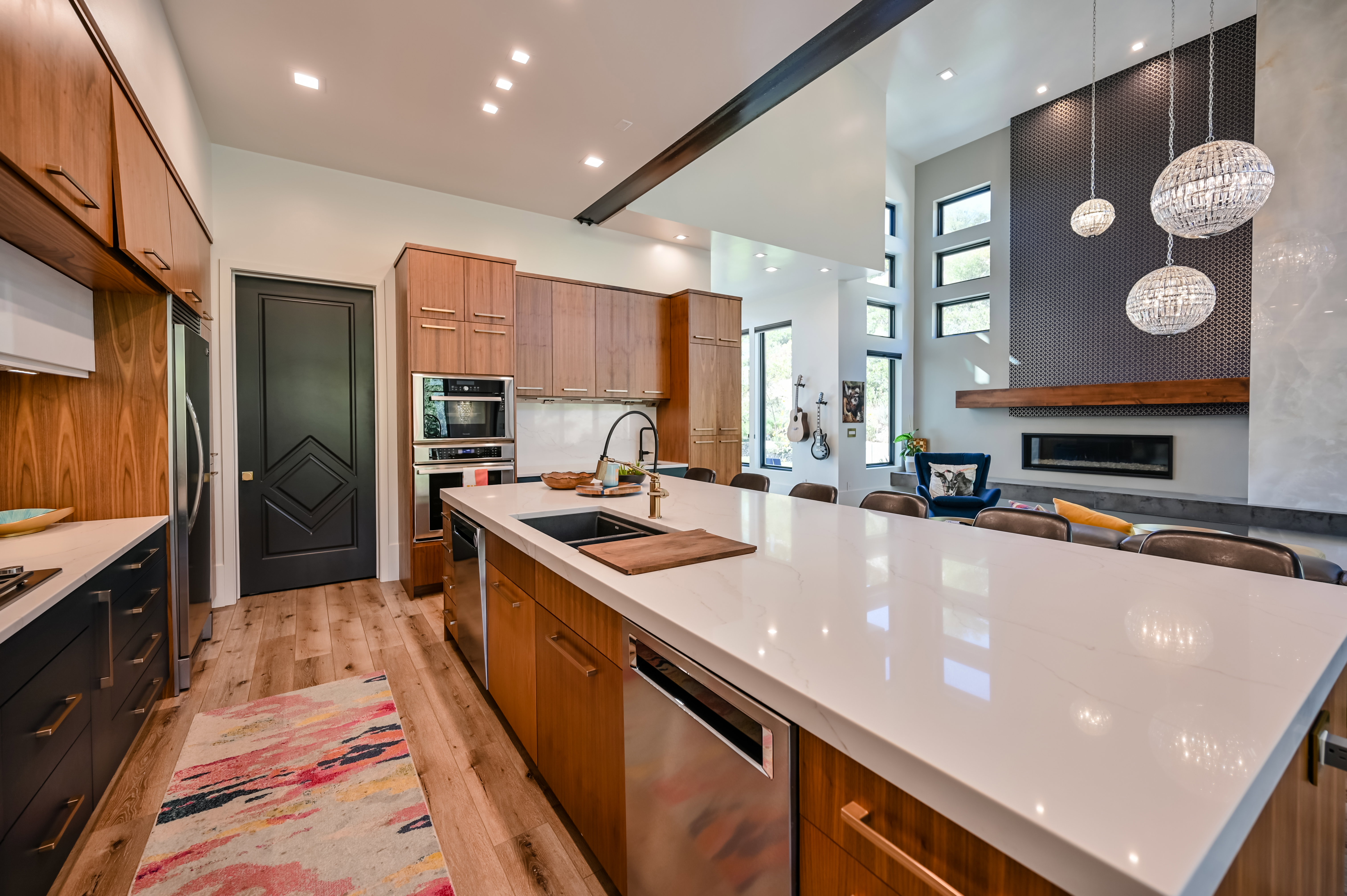 Open-concept kitchen featuring a spacious island with a light-toned countertop, integrated sink, and stainless steel dishwasher