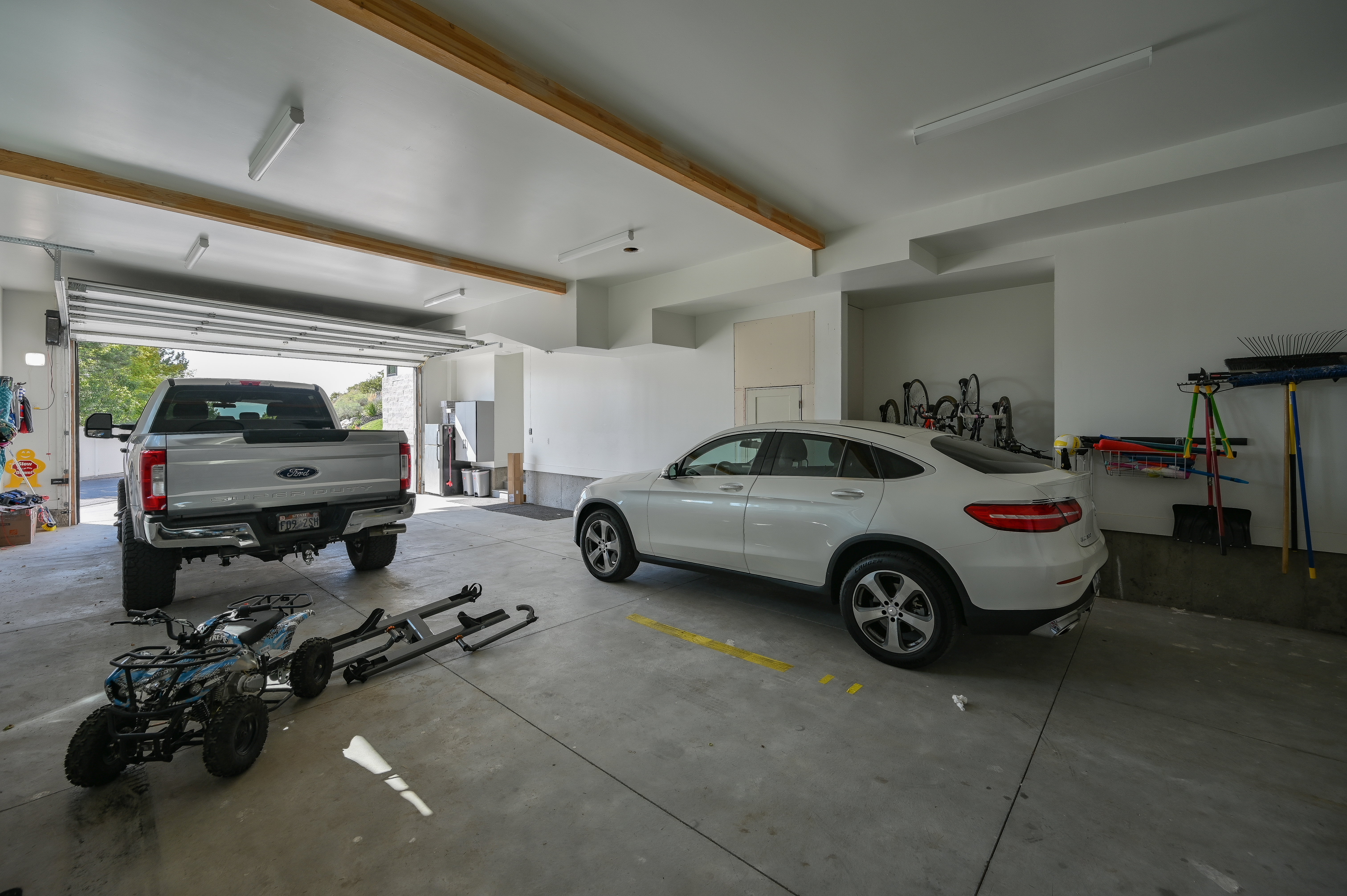 Spacious garage featuring a concrete floor, overhead lighting, and exposed wood ceiling beams