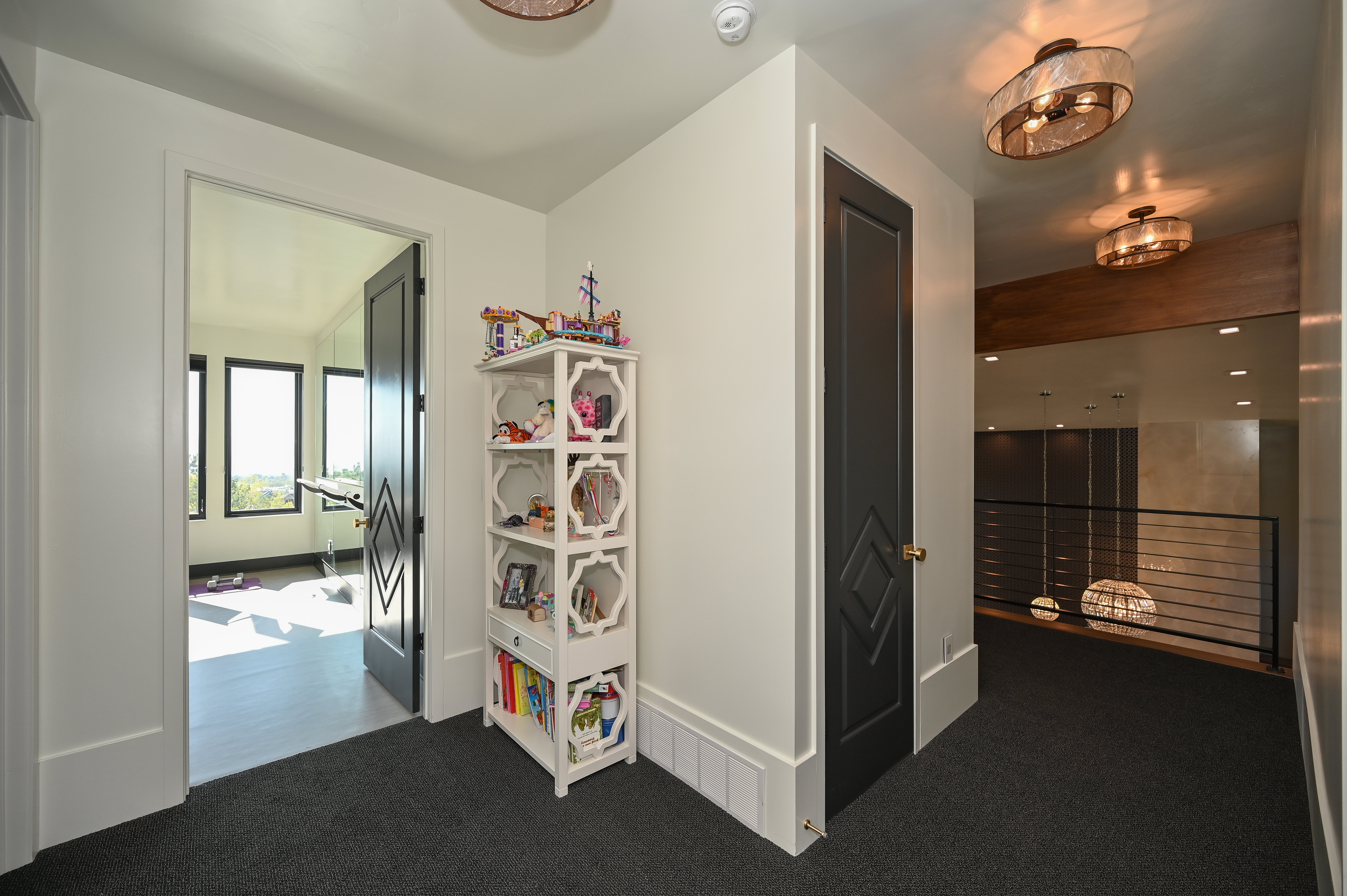 Upper-level hallway with dark gray carpet, white walls, and contemporary ceiling light fixtures