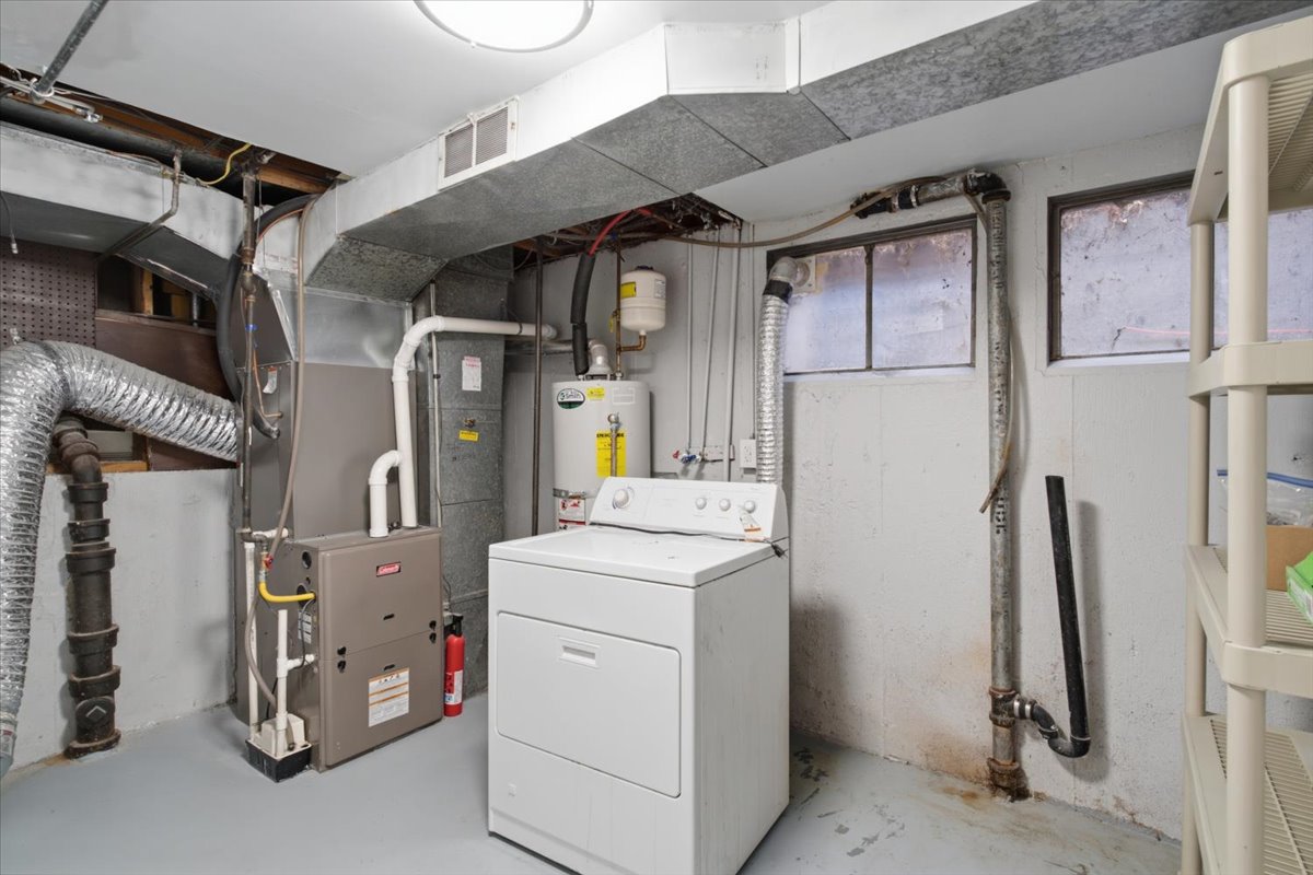 Utility room featuring a washer and dryer, water heater, furnace, and exposed ductwork