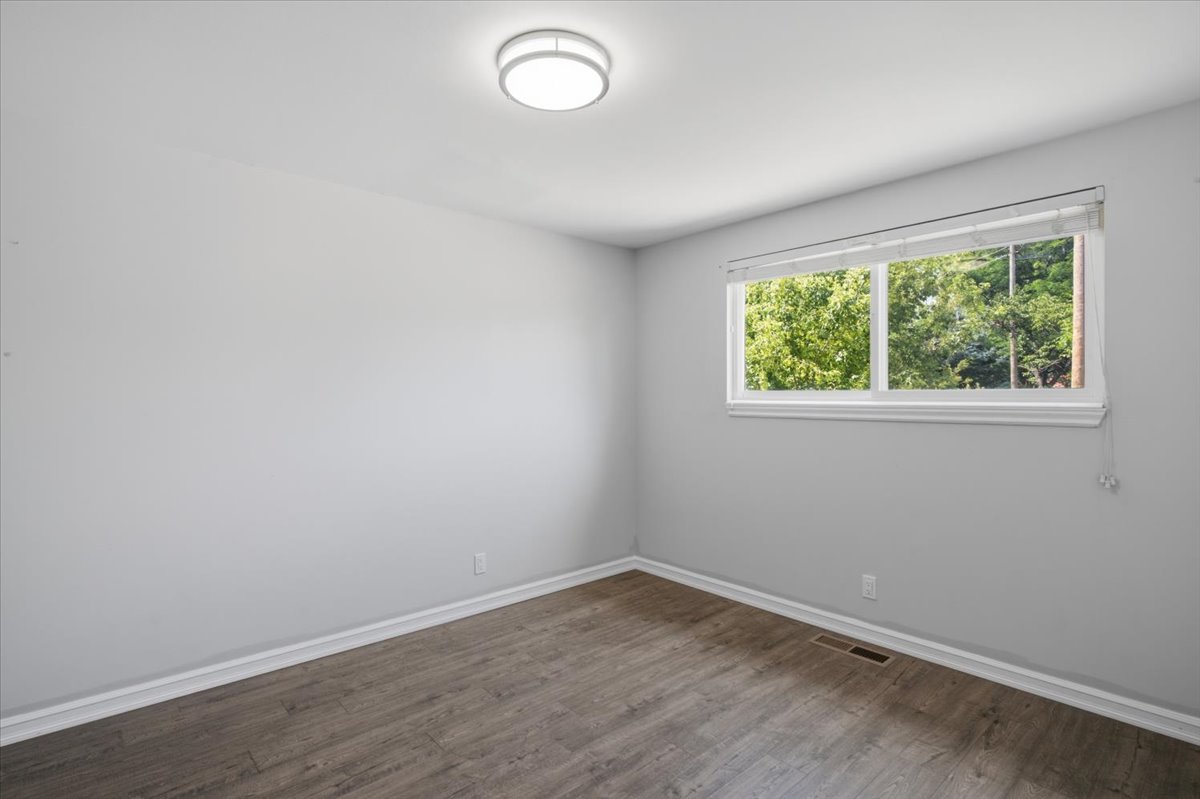 Bright room featuring a large window, a flush-mount ceiling light fixture, wood-finish flooring, white baseboards, and light gray painted walls