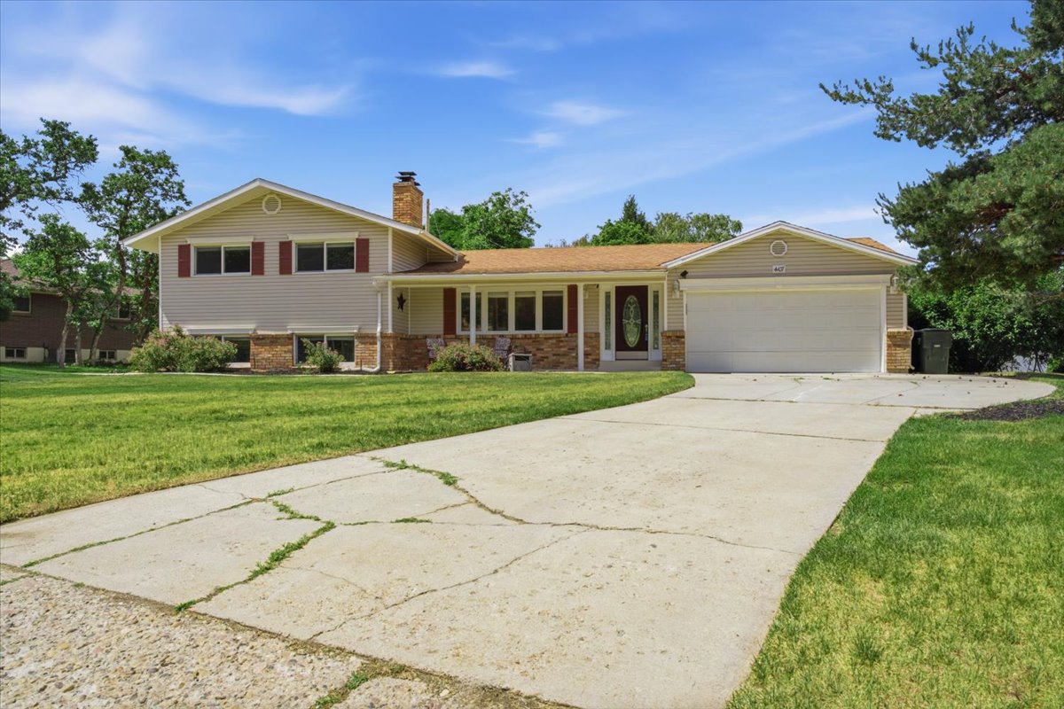 Two-story residence featuring light-colored siding with brick accents, a two-car garage, and a concrete driveway. Grass has been digitally enhanced. Grass is not fully green in all areas.