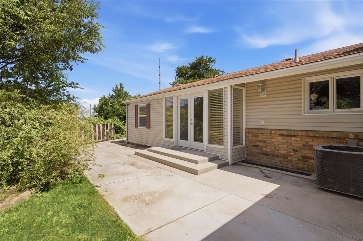 Concrete patio with two-step entry to double glass doors. Grass has been digitally enhanced. Grass is not fully green in all areas.