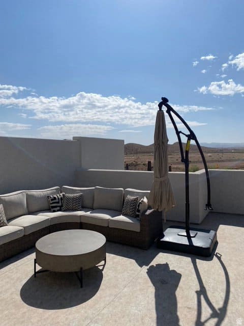 Expansive rooftop patio featuring a concrete surface, low perimeter walls, and distant mountain scenery