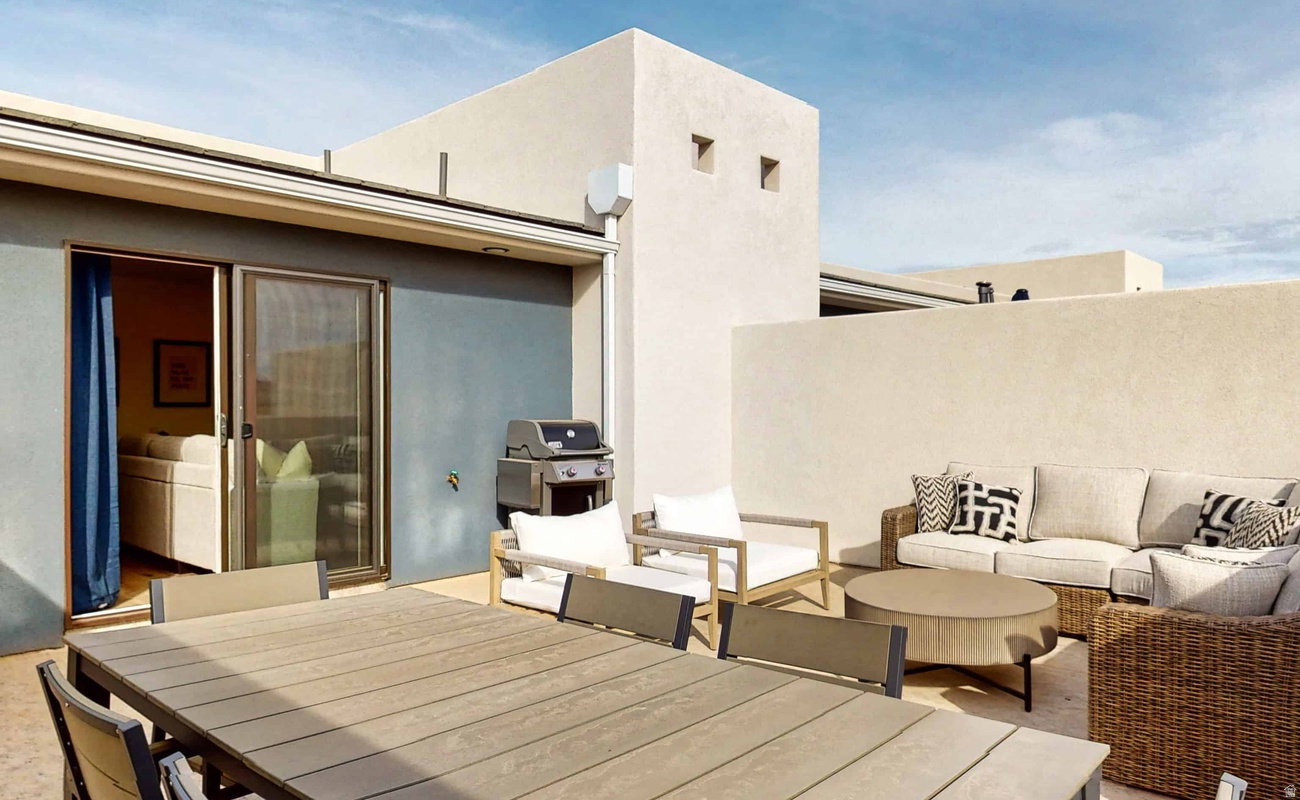 Rooftop terrace featuring light-toned stucco walls, a sliding glass door, and an outdoor grilling area