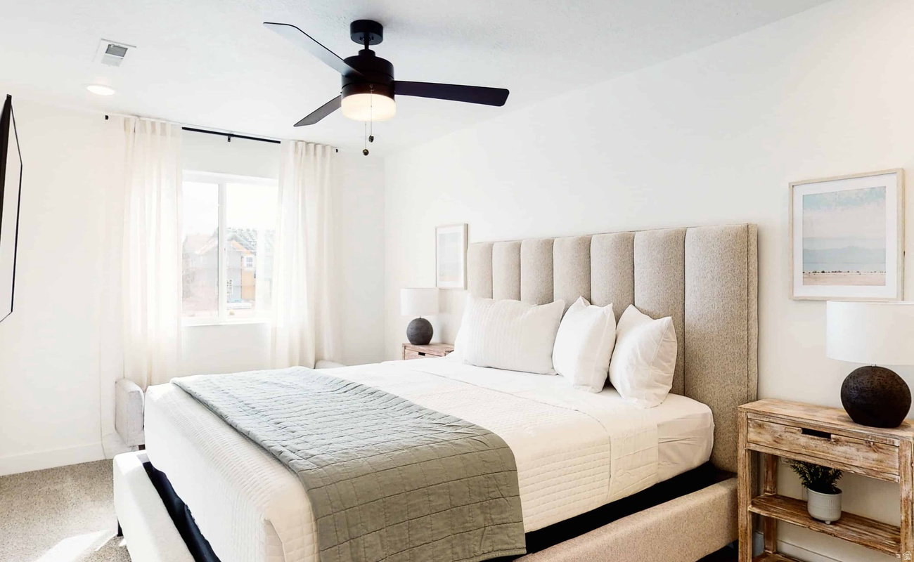 Spacious bedroom featuring light-colored walls and carpet flooring