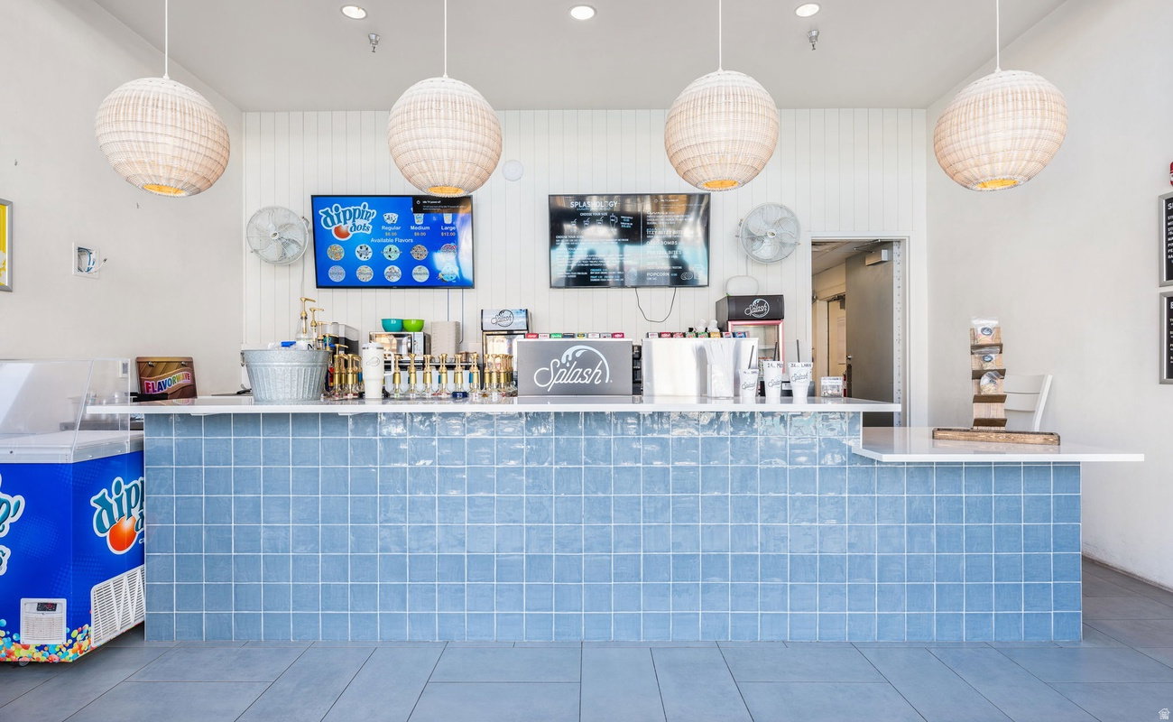 Tiled service counter with white solid surface countertop, four pendant light fixtures, and built-in menu boards