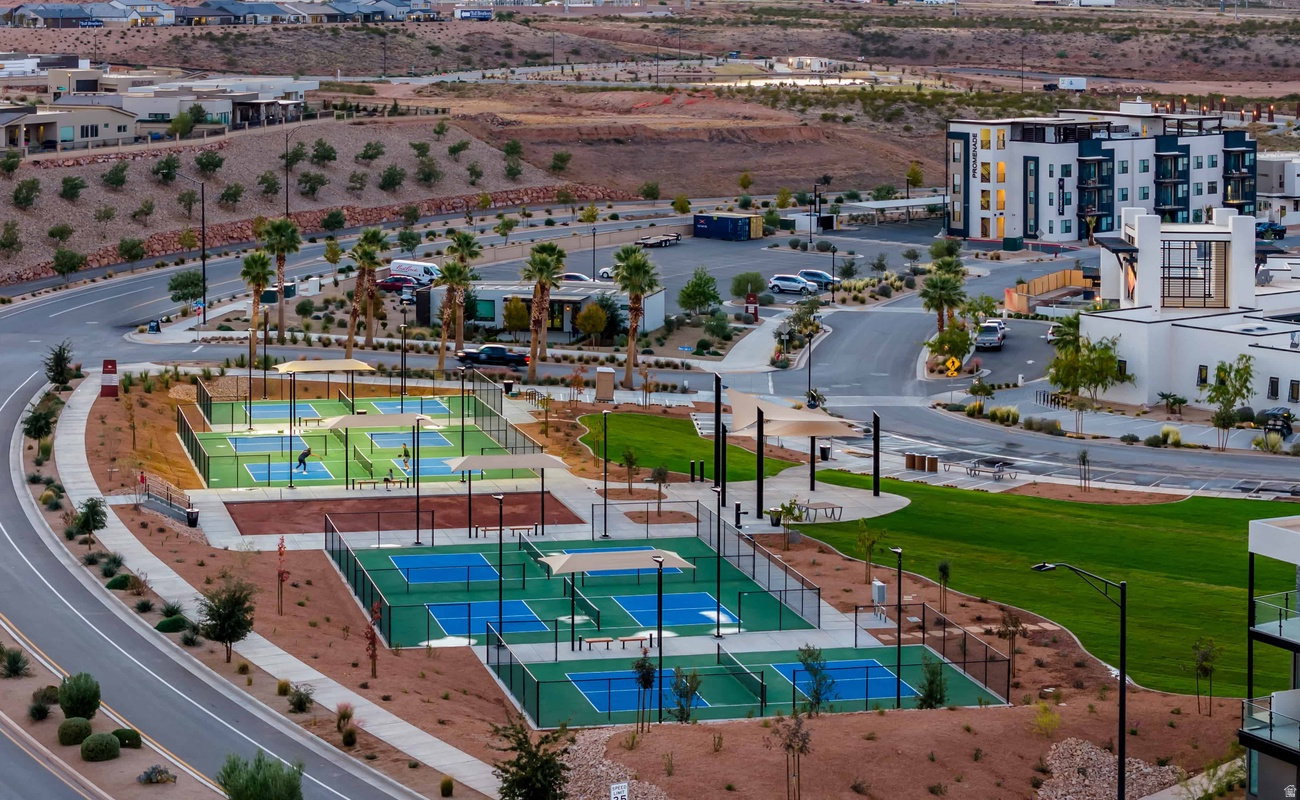 Multiple pickleball courts with green and blue playing surfaces, surrounded by fencing