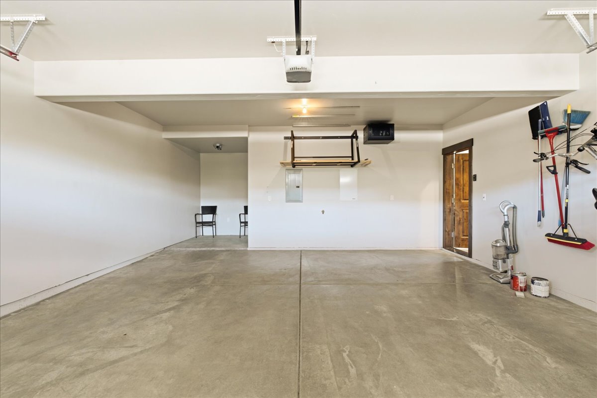 Spacious garage featuring a concrete floor, overhead garage door opener, and interior access door with wood-finish trim
