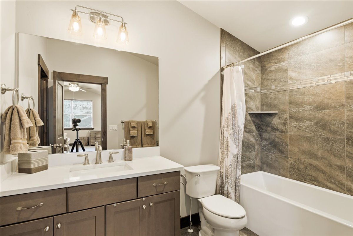 Bathroom featuring a wood-finish vanity with a white countertop and integrated sink, brushed nickel faucet, and a large mirror