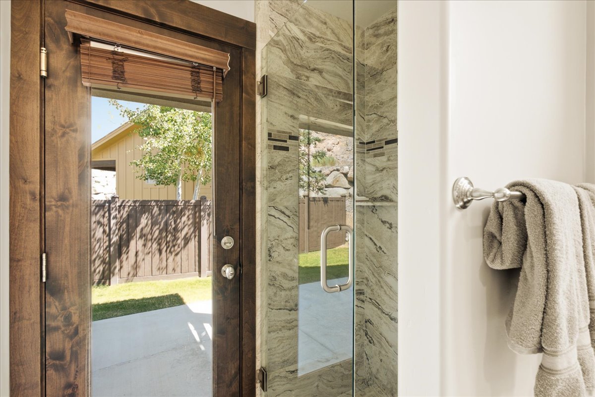 Glass-enclosed shower with stone-patterned tile, horizontal mosaic accent tile, and a polished chrome handle