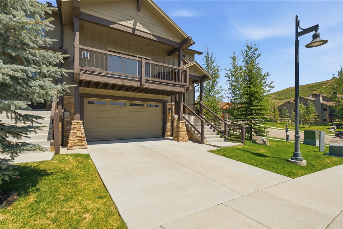 Multi-level residence featuring a two-car garage with windows, an upper-level balcony, and stone column accents