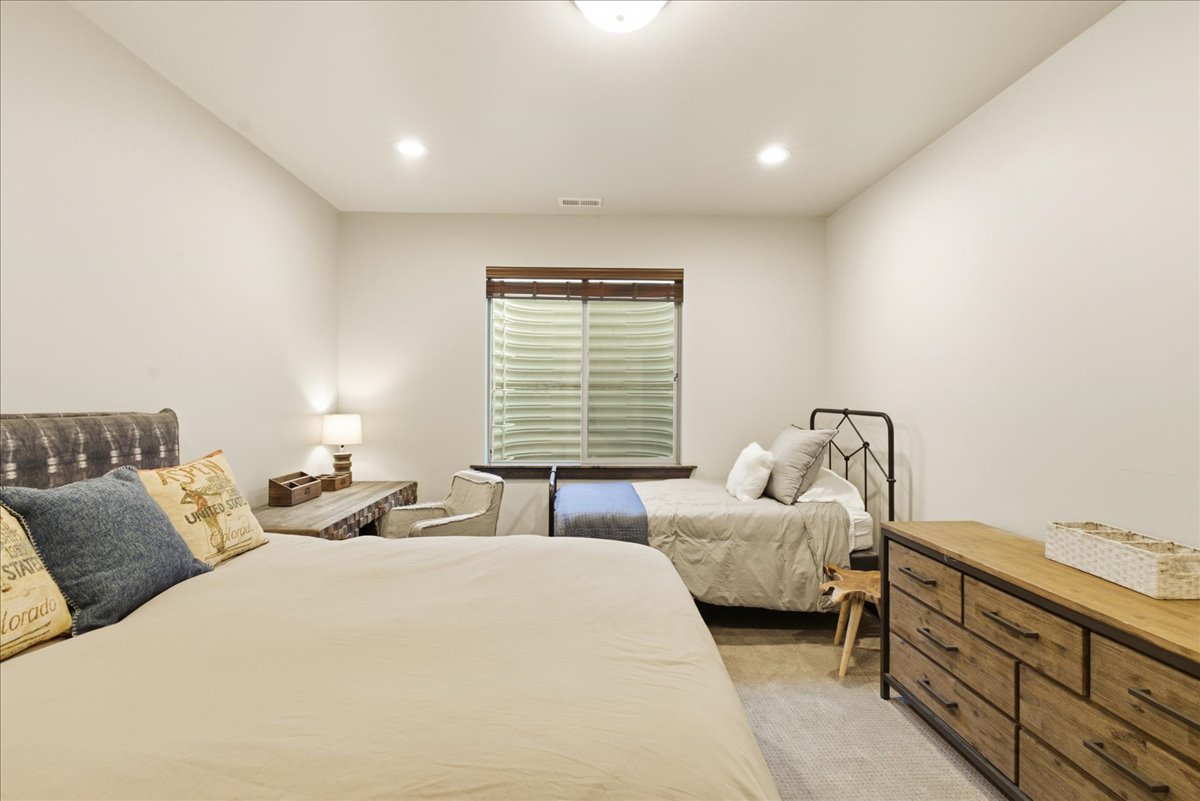 Bedroom featuring light neutral wall tones, recessed lighting, a window with wood-finish blinds, and carpeted flooring