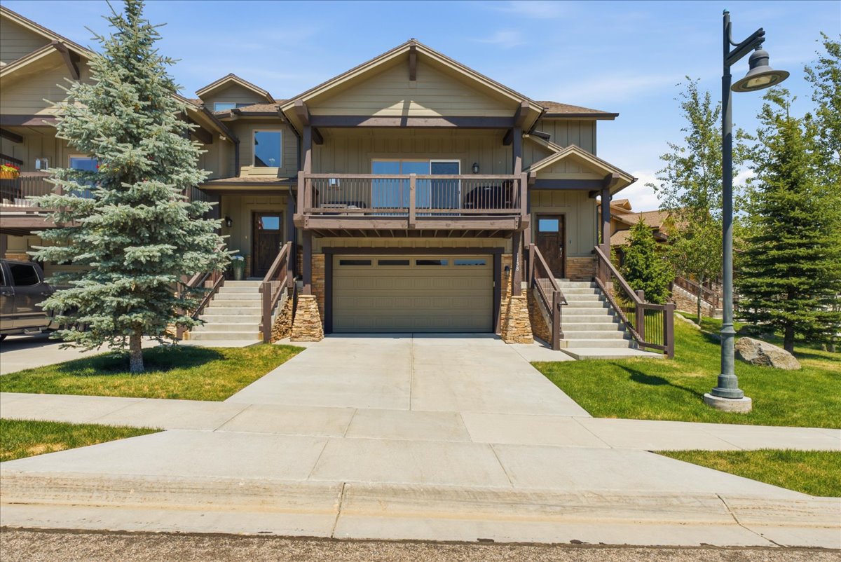 Multi-level townhome featuring a neutral-toned exterior with stone accents and a spacious attached garage