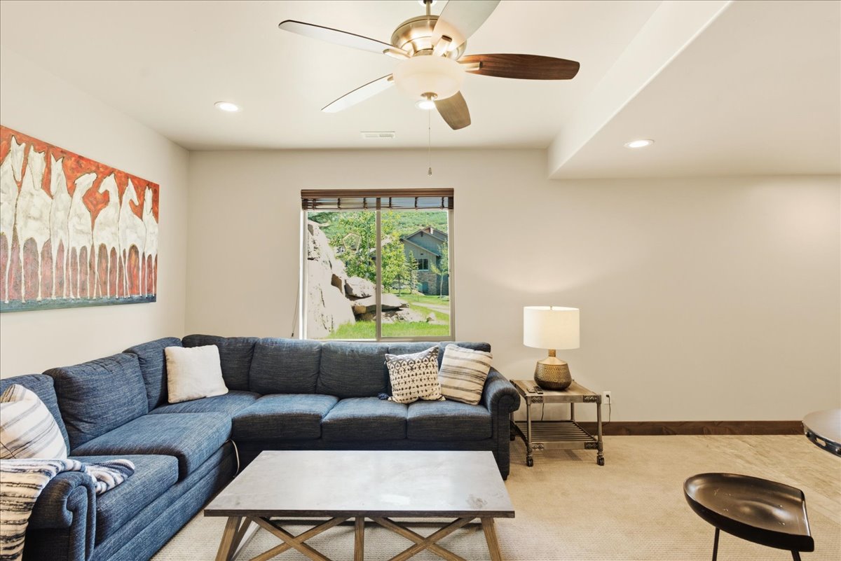 Carpeted living space with a ceiling fan, recessed lighting, and a large window