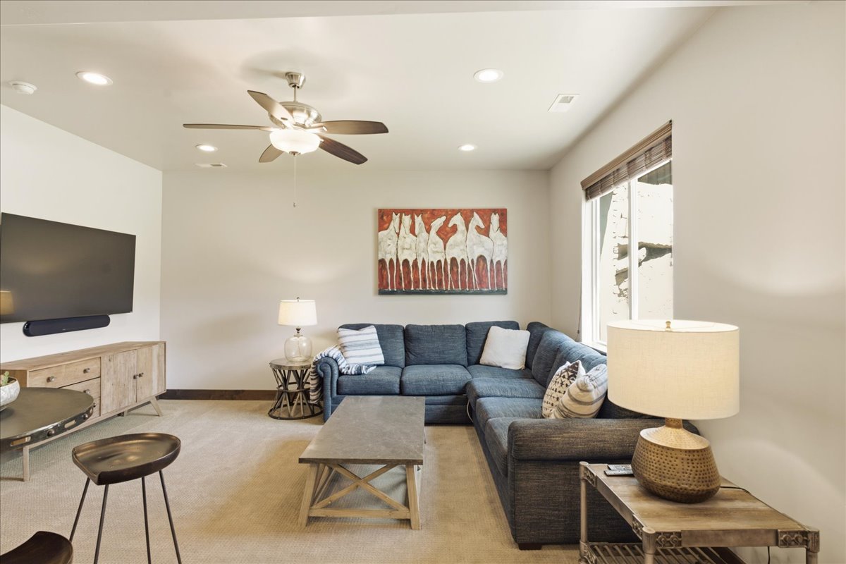 Carpeted living area featuring recessed lighting, a ceiling fan with integrated light, and natural light from a window with blinds