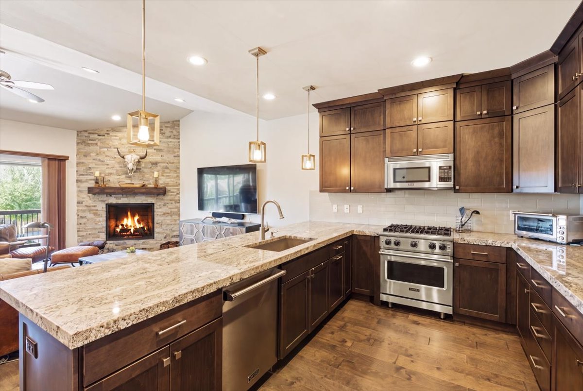 Gourmet kitchen featuring granite countertops, dark wood cabinetry, stainless steel appliances, and wood-finish flooring