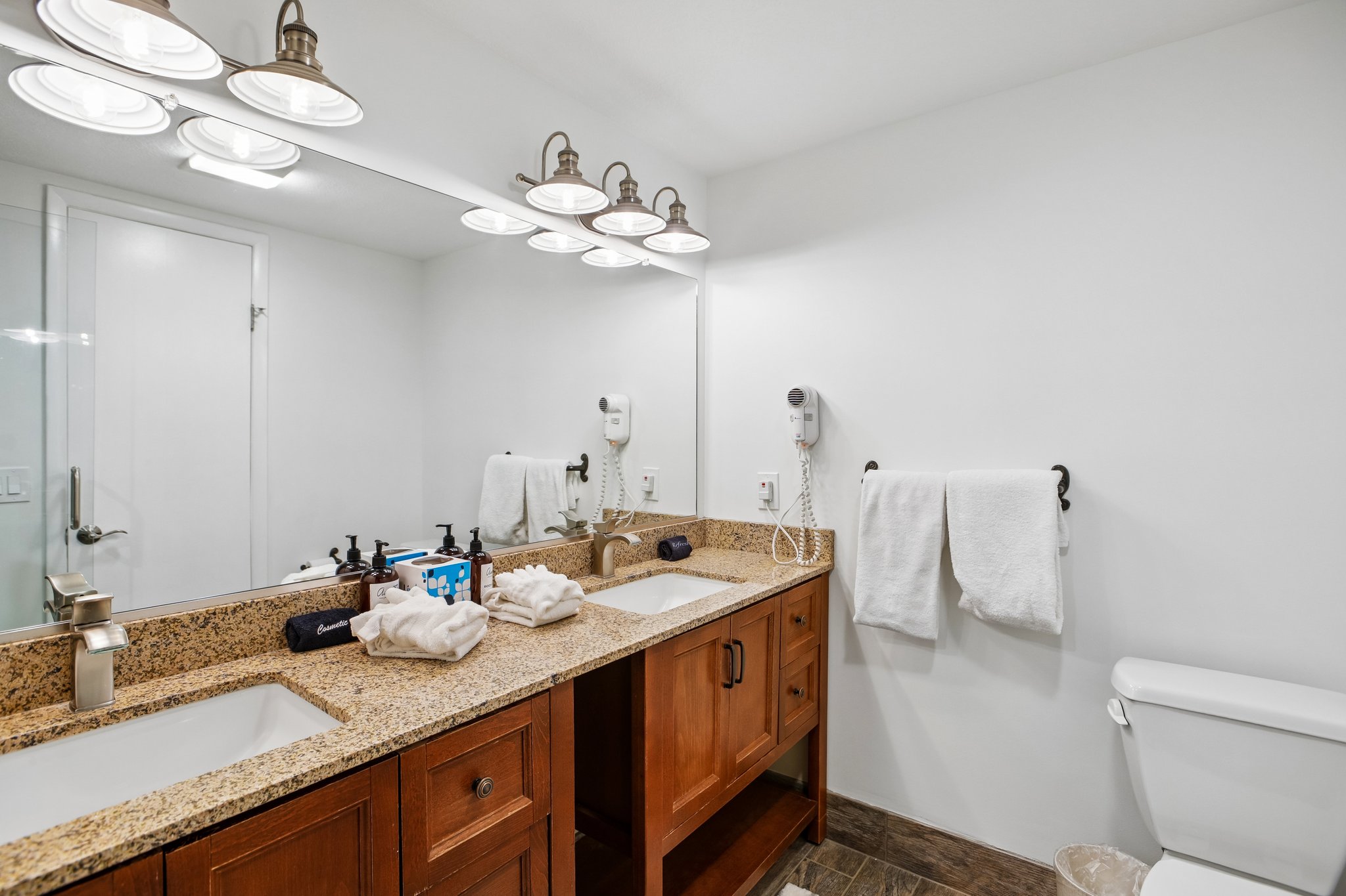 Dual undermount sinks set within a granite countertop, complemented by warm wood-finish cabinetry