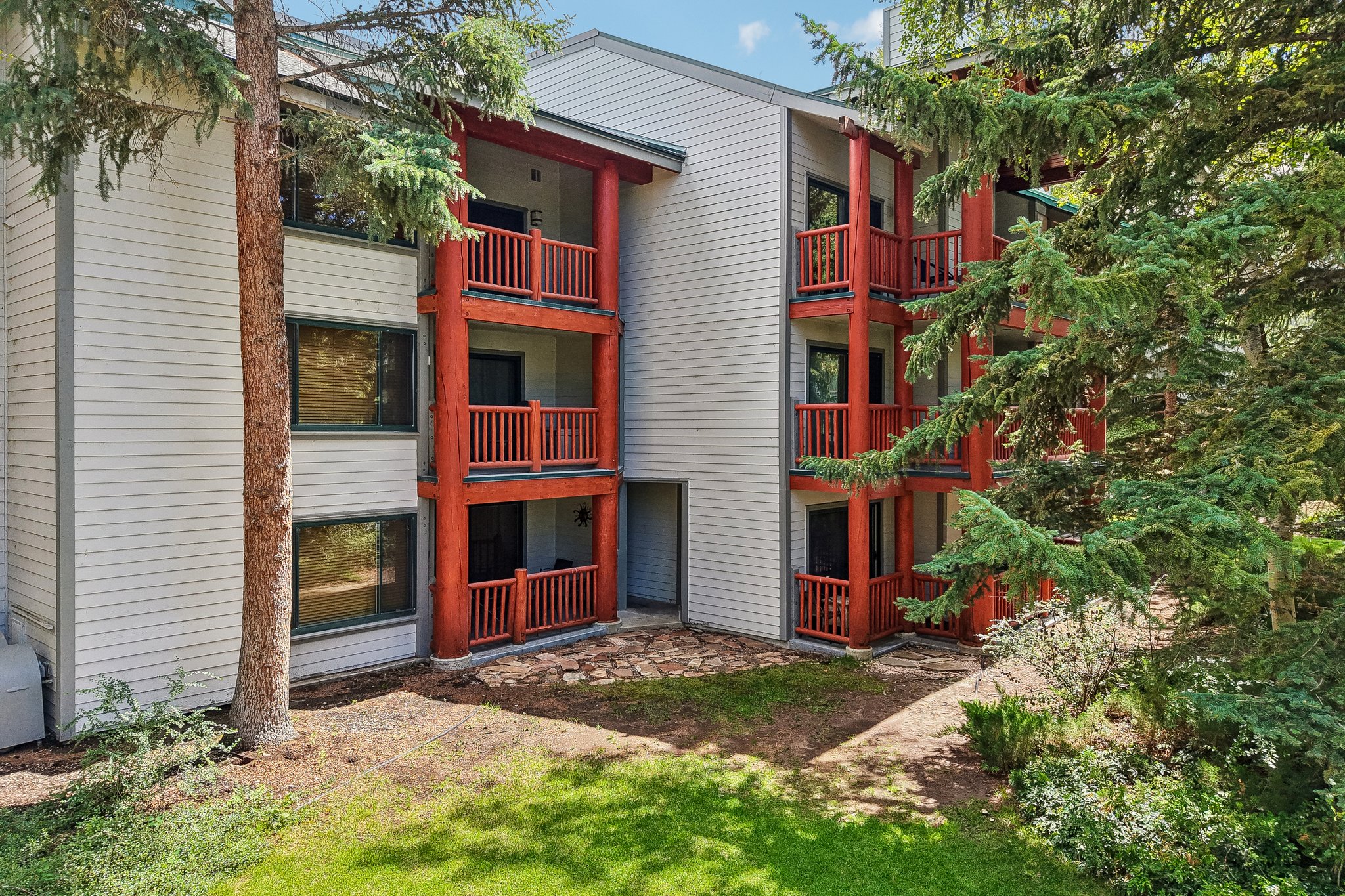Multi-story building featuring light-colored siding and red-toned exposed structural beams
