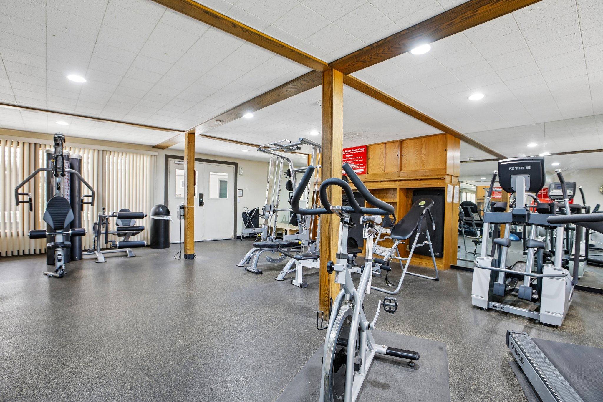 Spacious fitness area featuring rubber flooring, recessed lighting, and mirrored walls