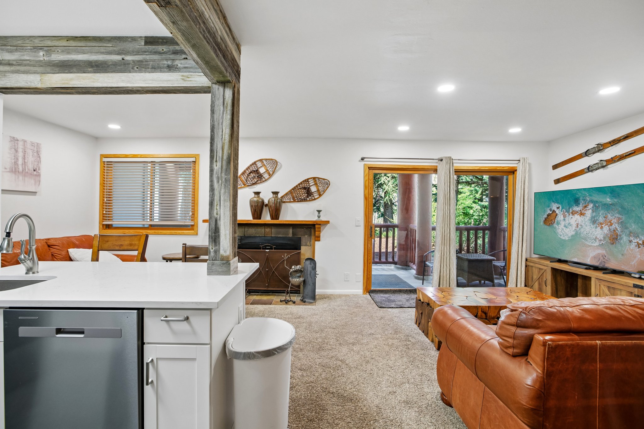 Open-concept living area featuring a kitchen island with white countertop, integrated stainless steel dishwasher, and recessed lighting