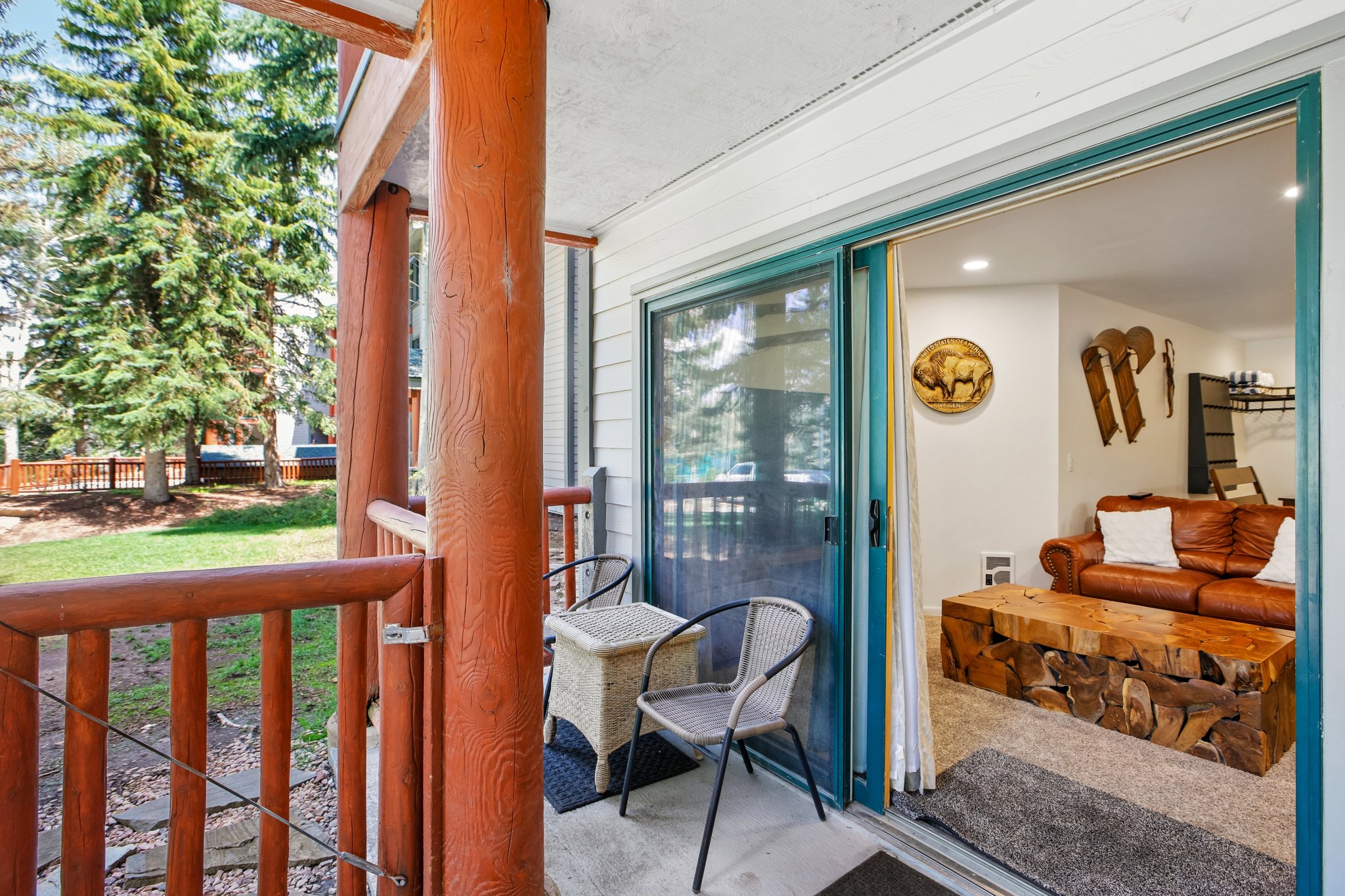 Outdoor patio with natural wood railings and posts, offering direct access to a living area through a sliding glass door