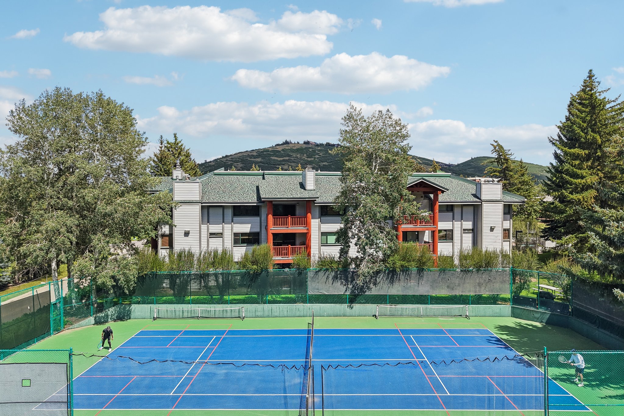 Full-size tennis court featuring a blue playing surface with white and red court lines