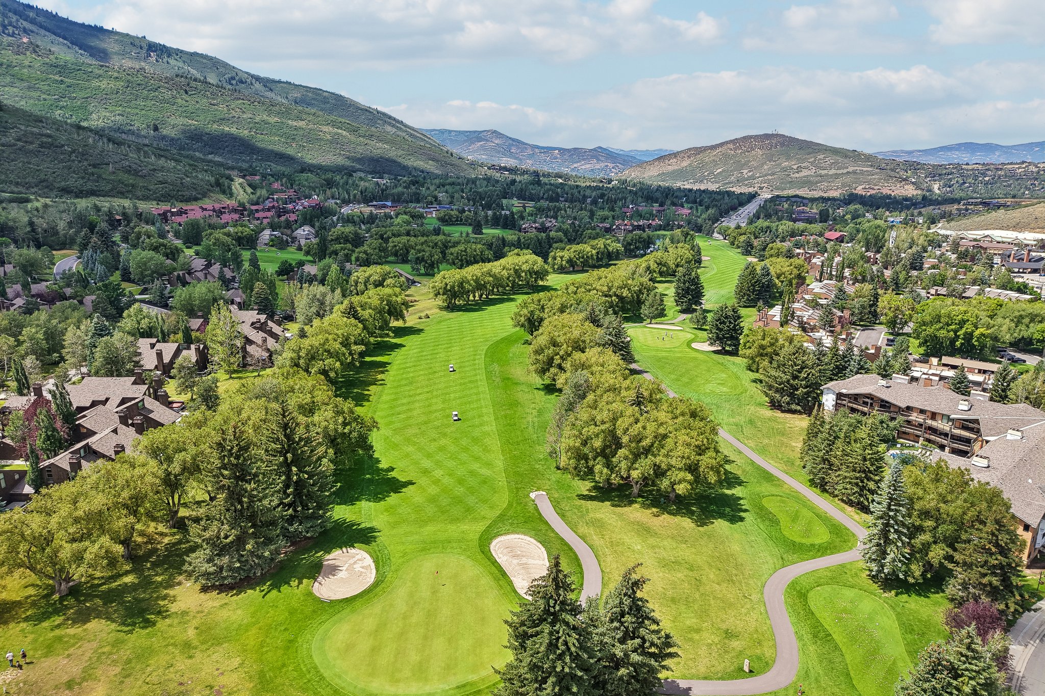 Expansive golf course fairway bordered by mature trees and residential properties