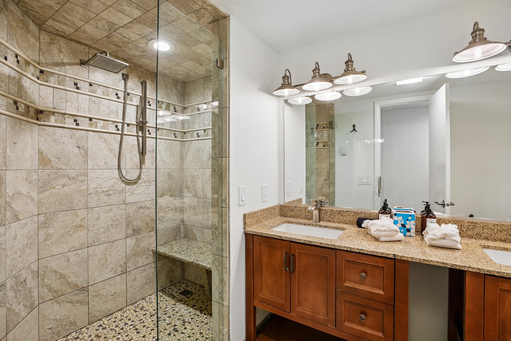 Walk-in shower with natural stone-look tile, built-in bench, and rain showerhead