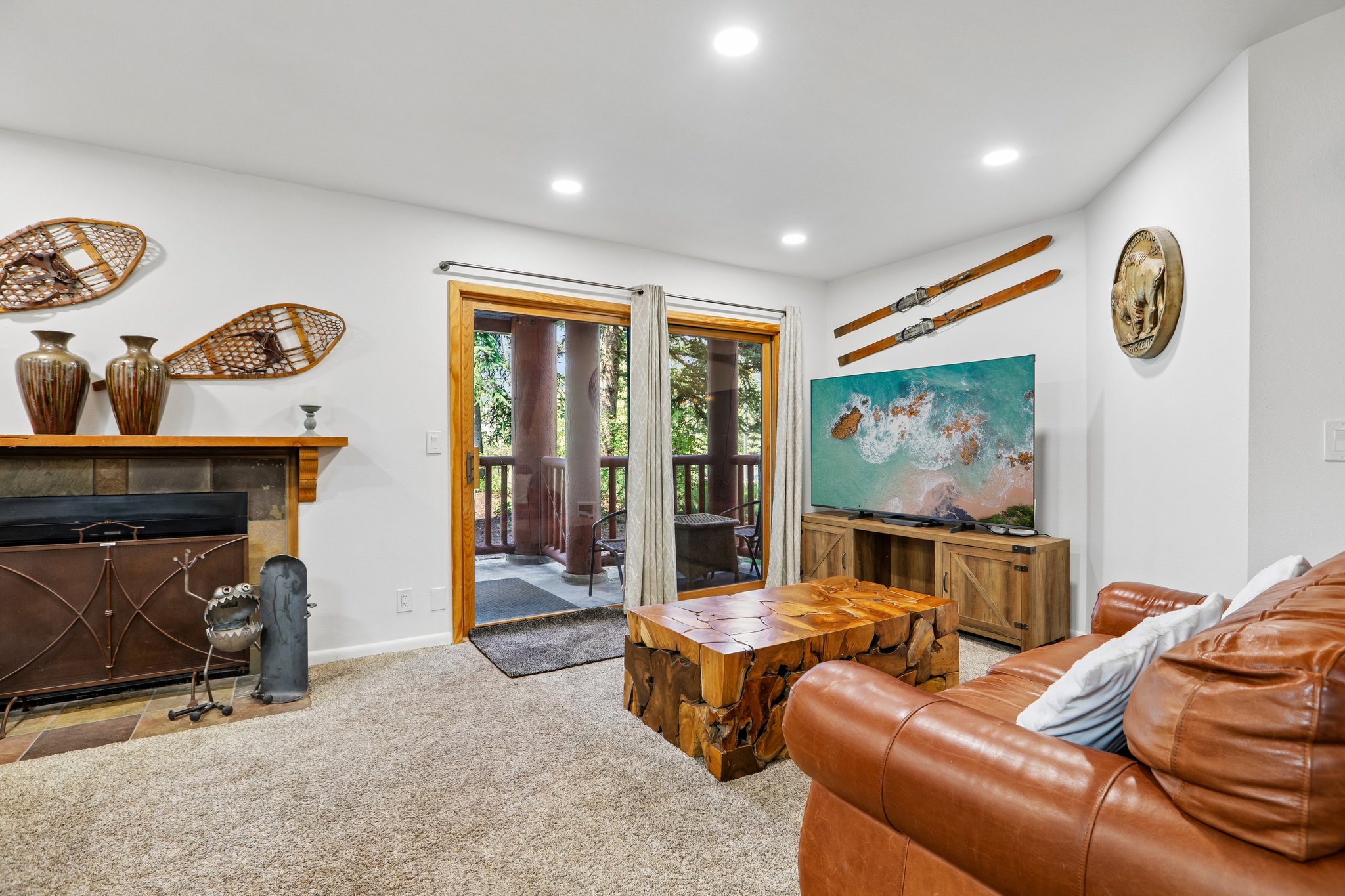 Living area featuring carpet flooring, recessed lighting, and a stone-surround fireplace with a wood mantle