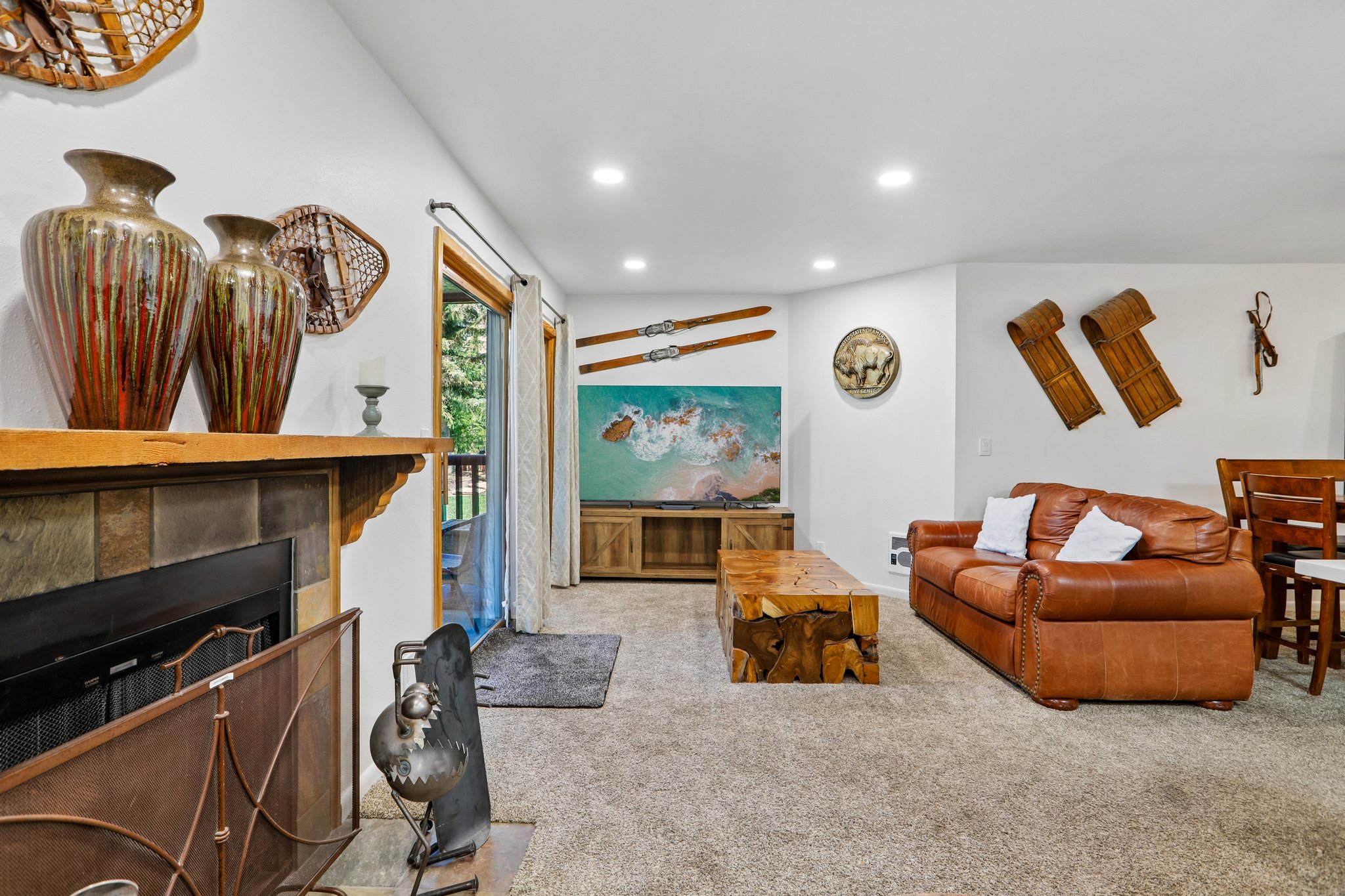 Living area featuring a stone-faced fireplace with a wood mantle, carpet flooring, recessed lighting, and a glass sliding door
