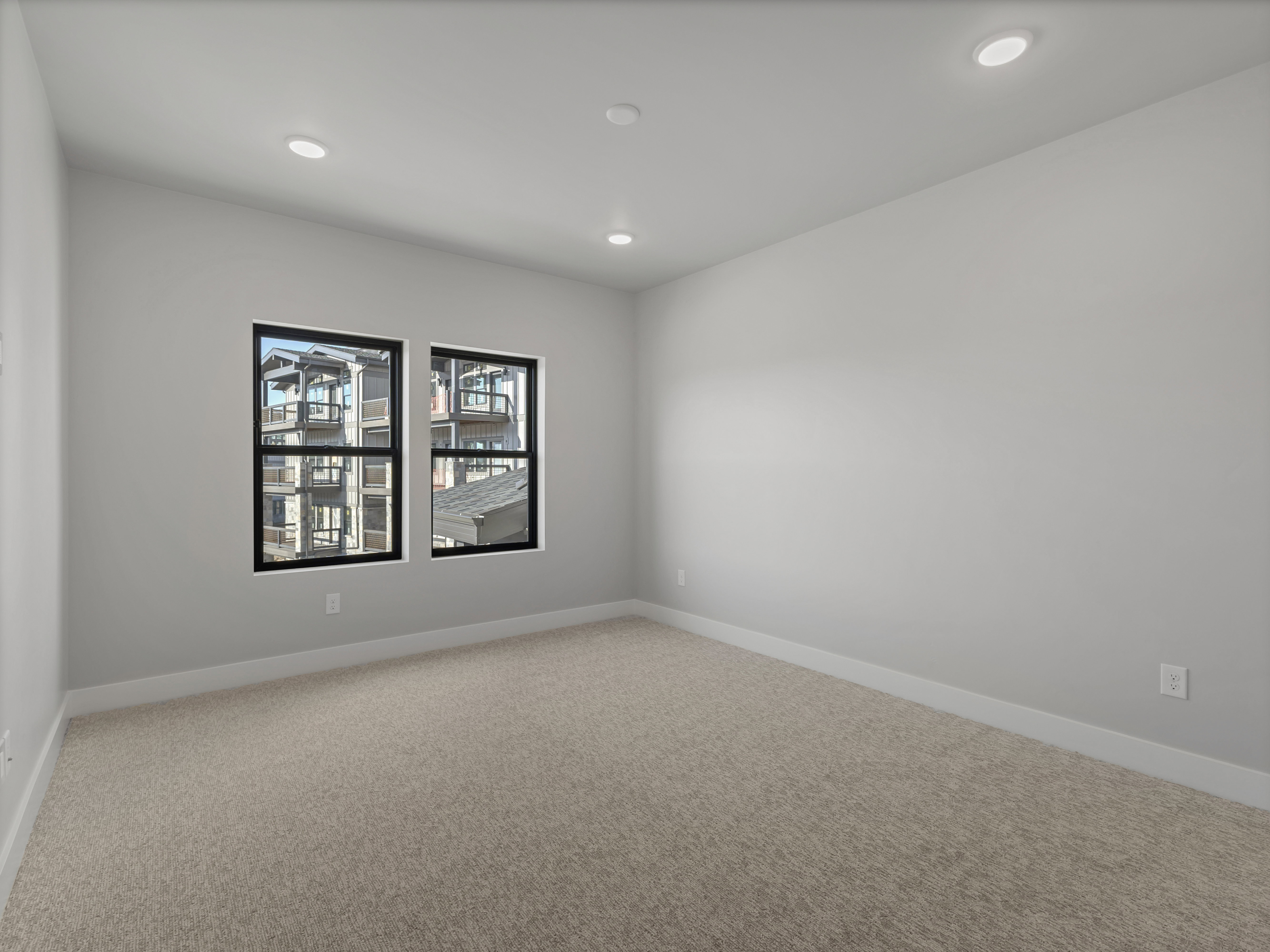 Neutral-toned room featuring a light beige carpet, white baseboards, and light gray painted walls