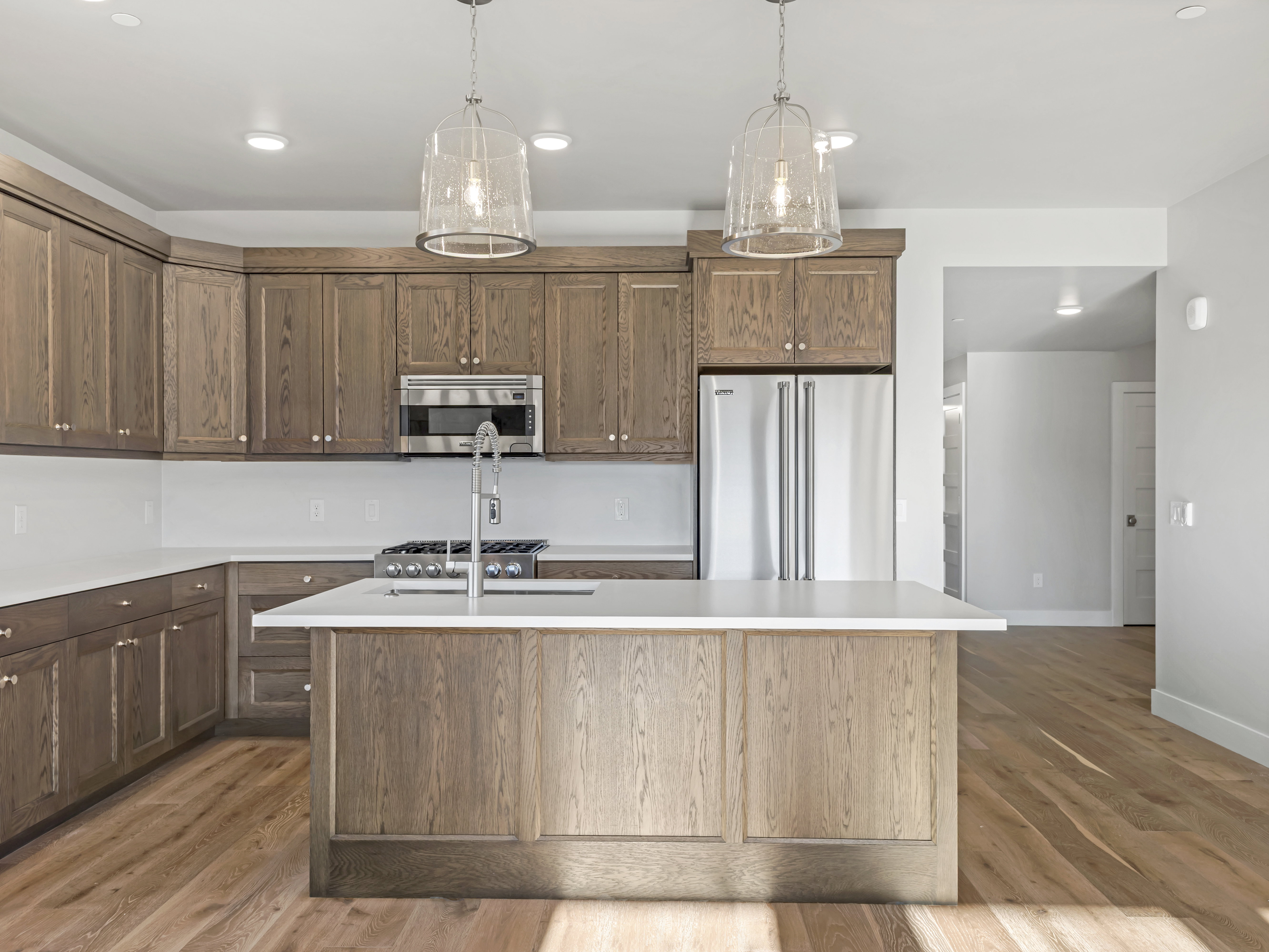 Modern kitchen featuring wood-finish cabinetry, stainless steel appliances, a center island with countertop seating, recessed lighting, and wood-finish flooring