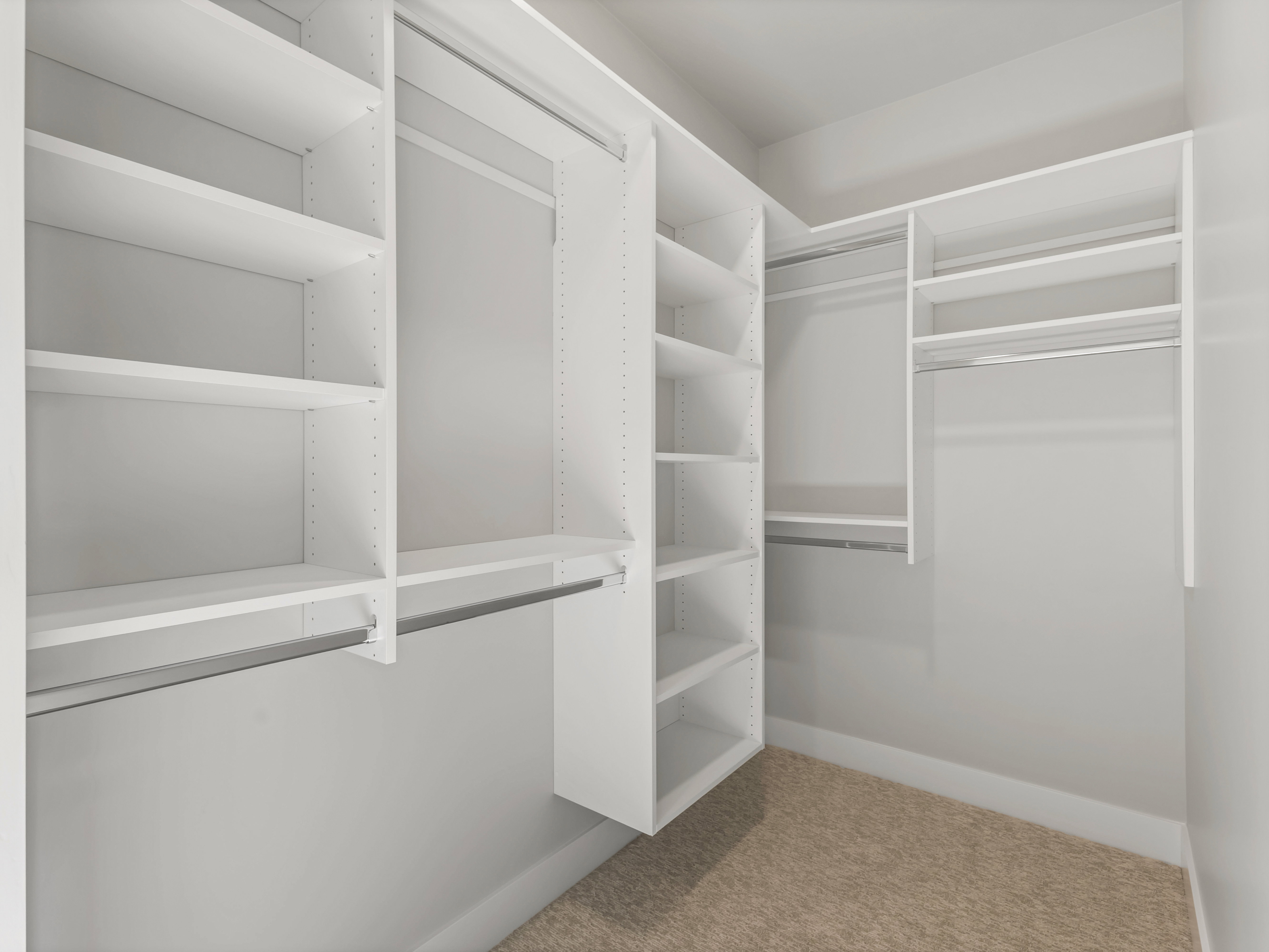 Custom closet system featuring white shelving units, multiple hanging rods, and adjustable shelves
