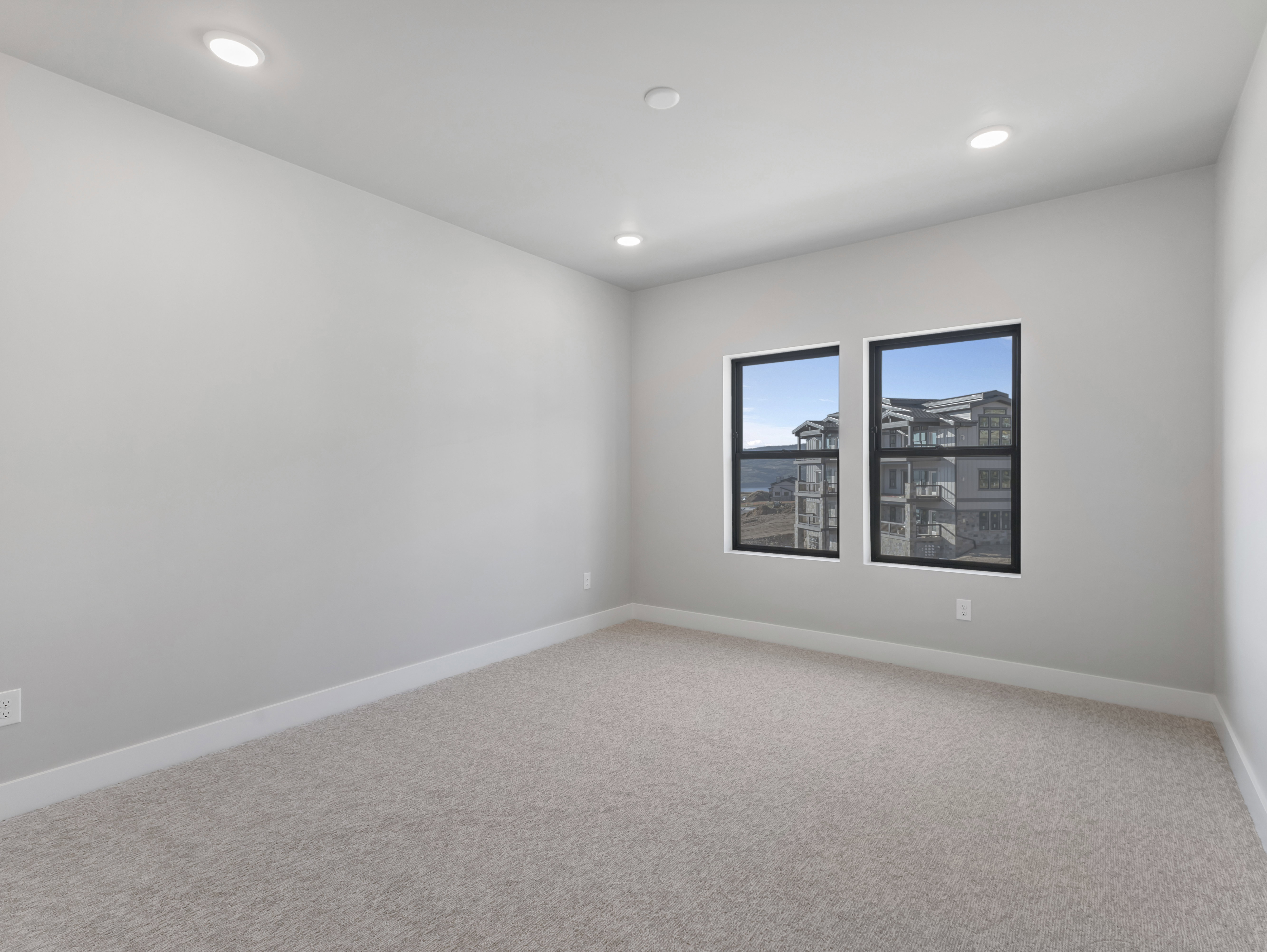 Recessed lighting illuminates this room featuring wall-to-wall carpeting and contemporary windows with black frames