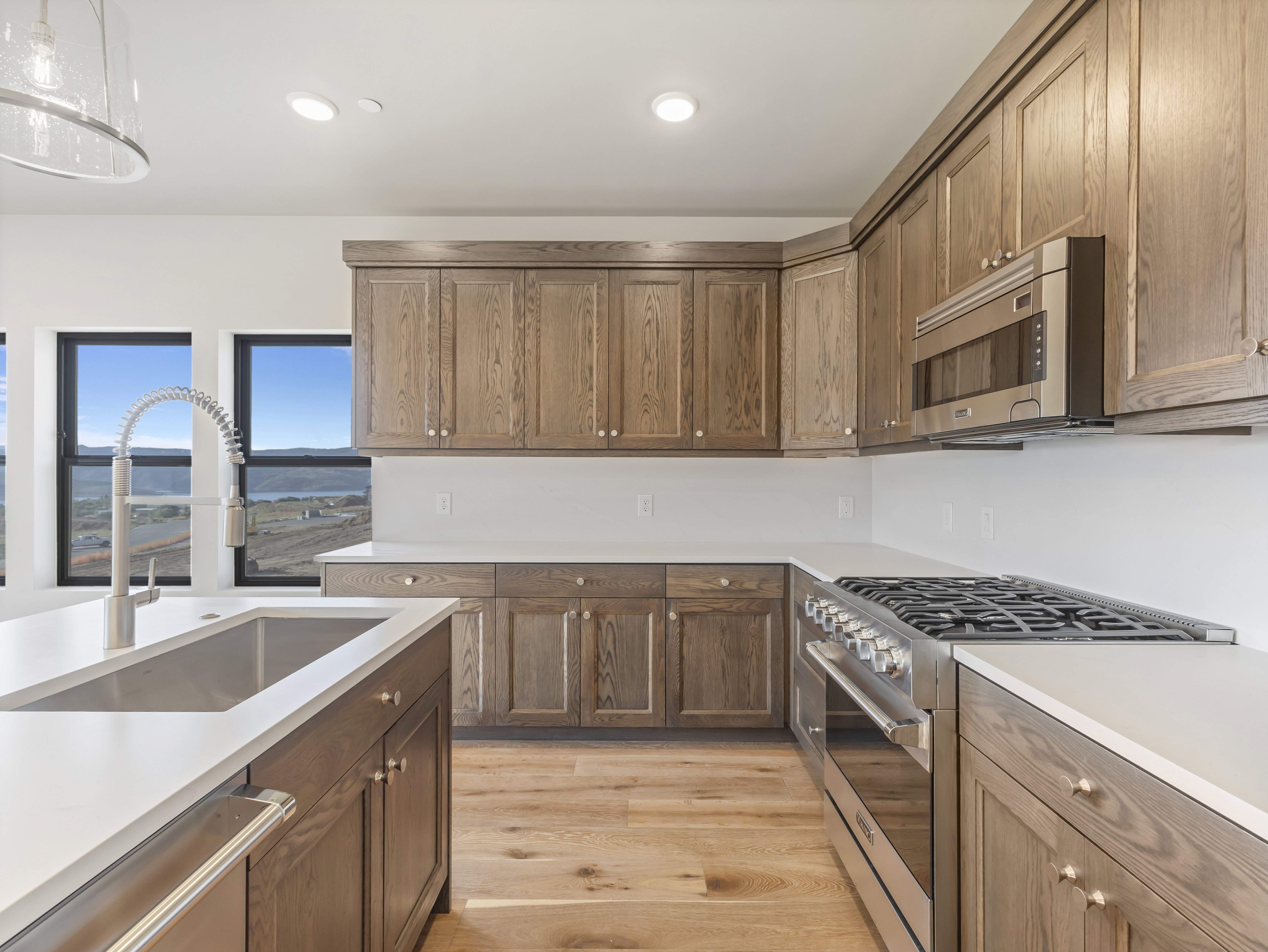 Kitchen featuring wood cabinetry, stainless steel appliances, white countertops, and wood-finish flooring