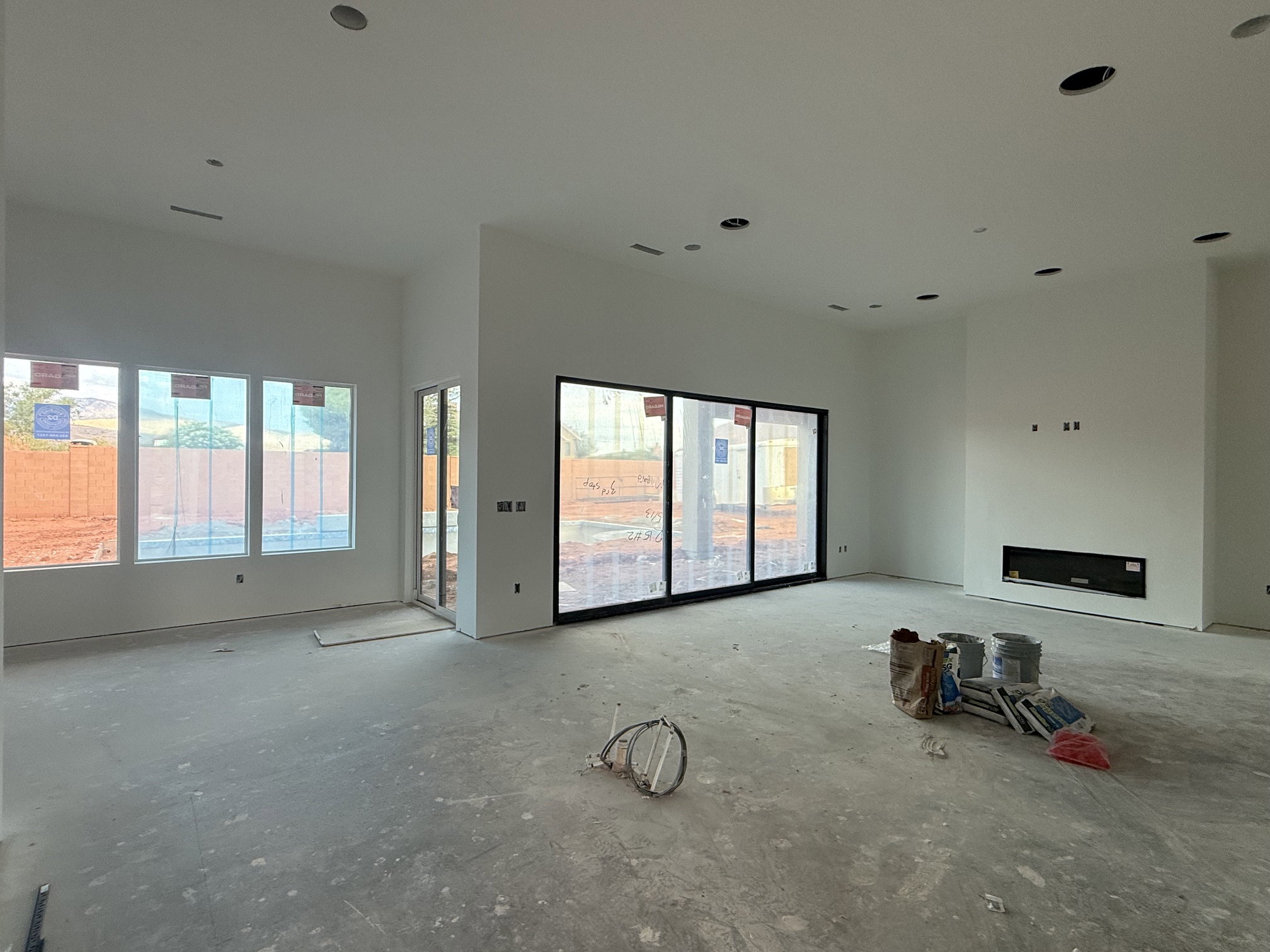 Spacious interior featuring multiple large windows, a multi-panel sliding glass door, a built-in linear fireplace, and recessed lighting fixtures