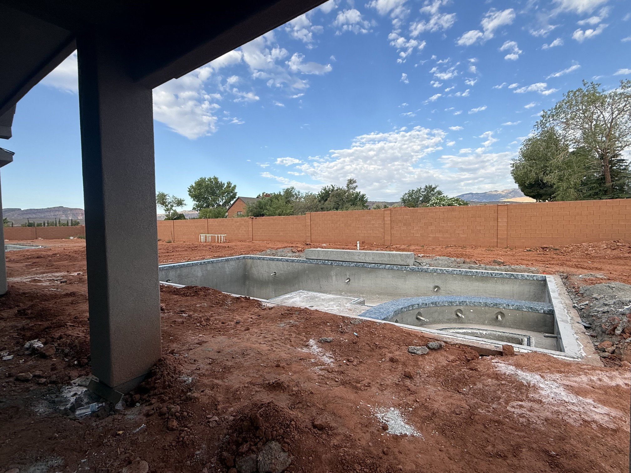 Unfinished swimming pool with an integrated spa, surrounded by raw earth